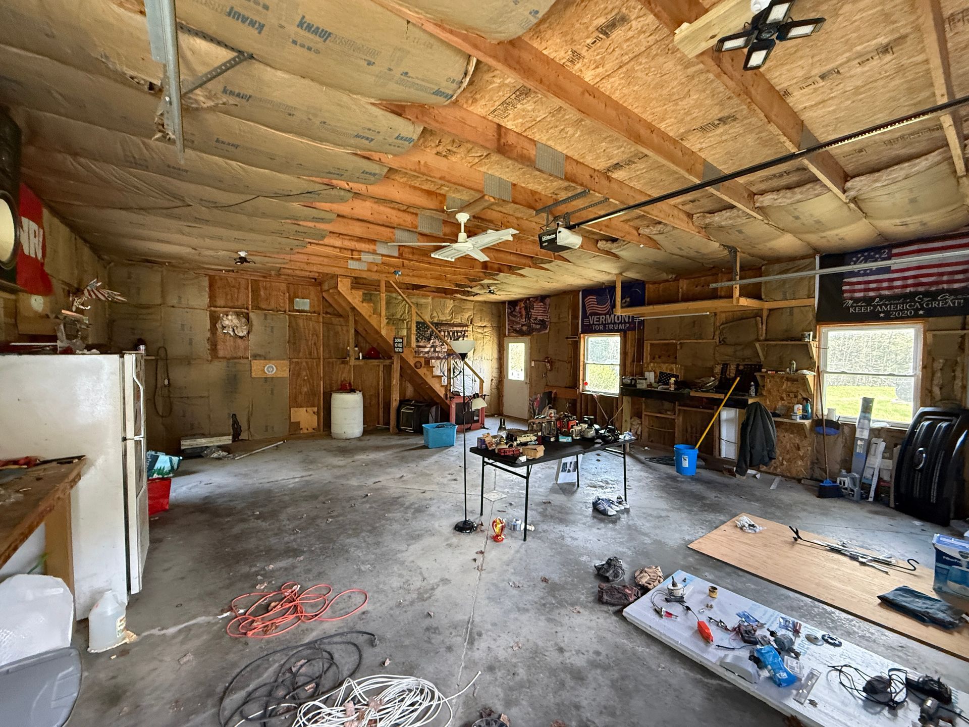 Garage with exposed rafters, tools, and workbench under construction