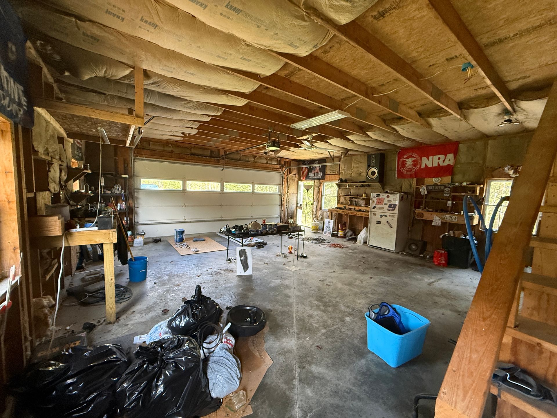Garage interior with exposed ceiling beams, tools, bins