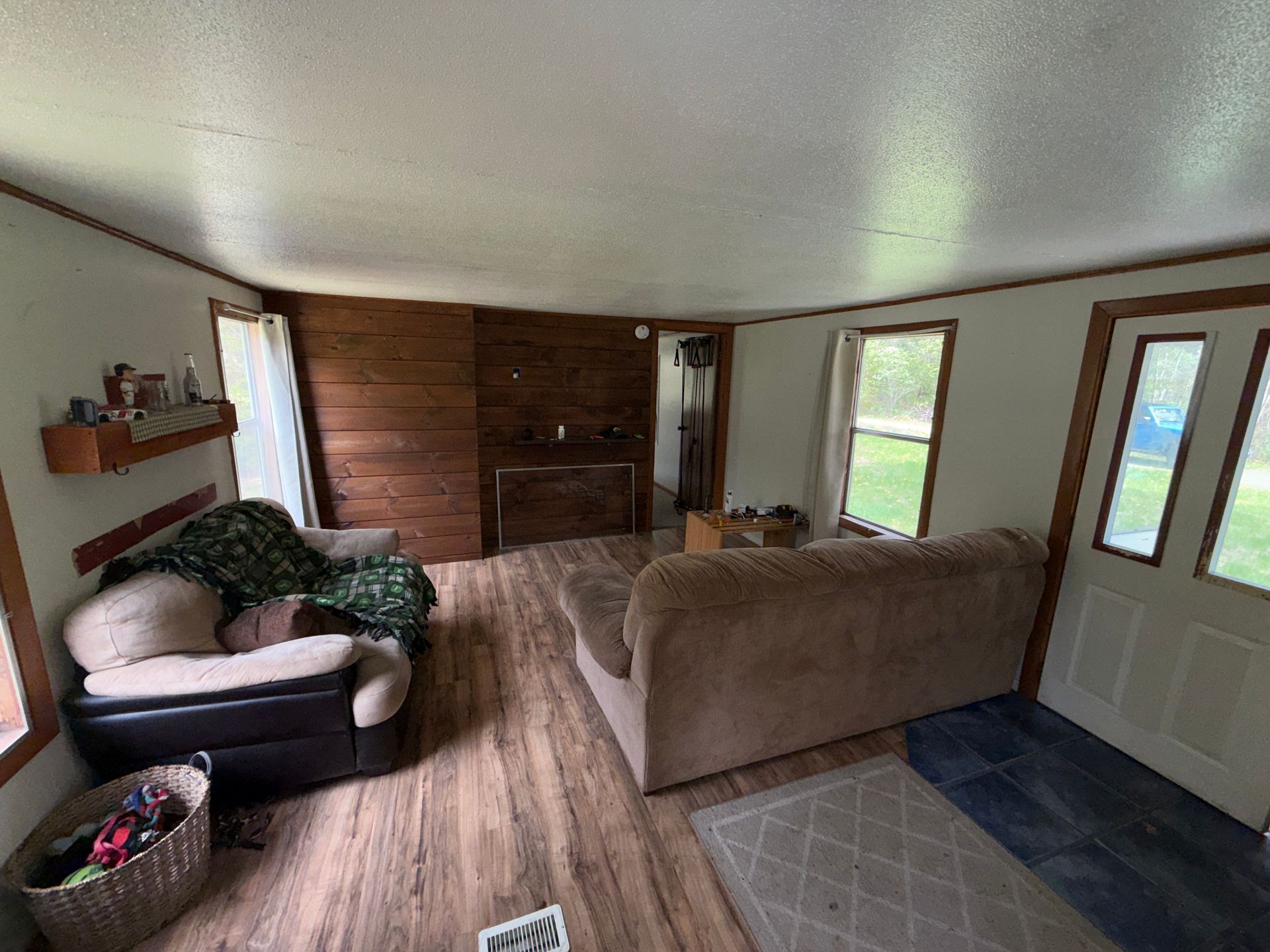 Cozy living room with sofas, wood-paneled wall, and front door with windows