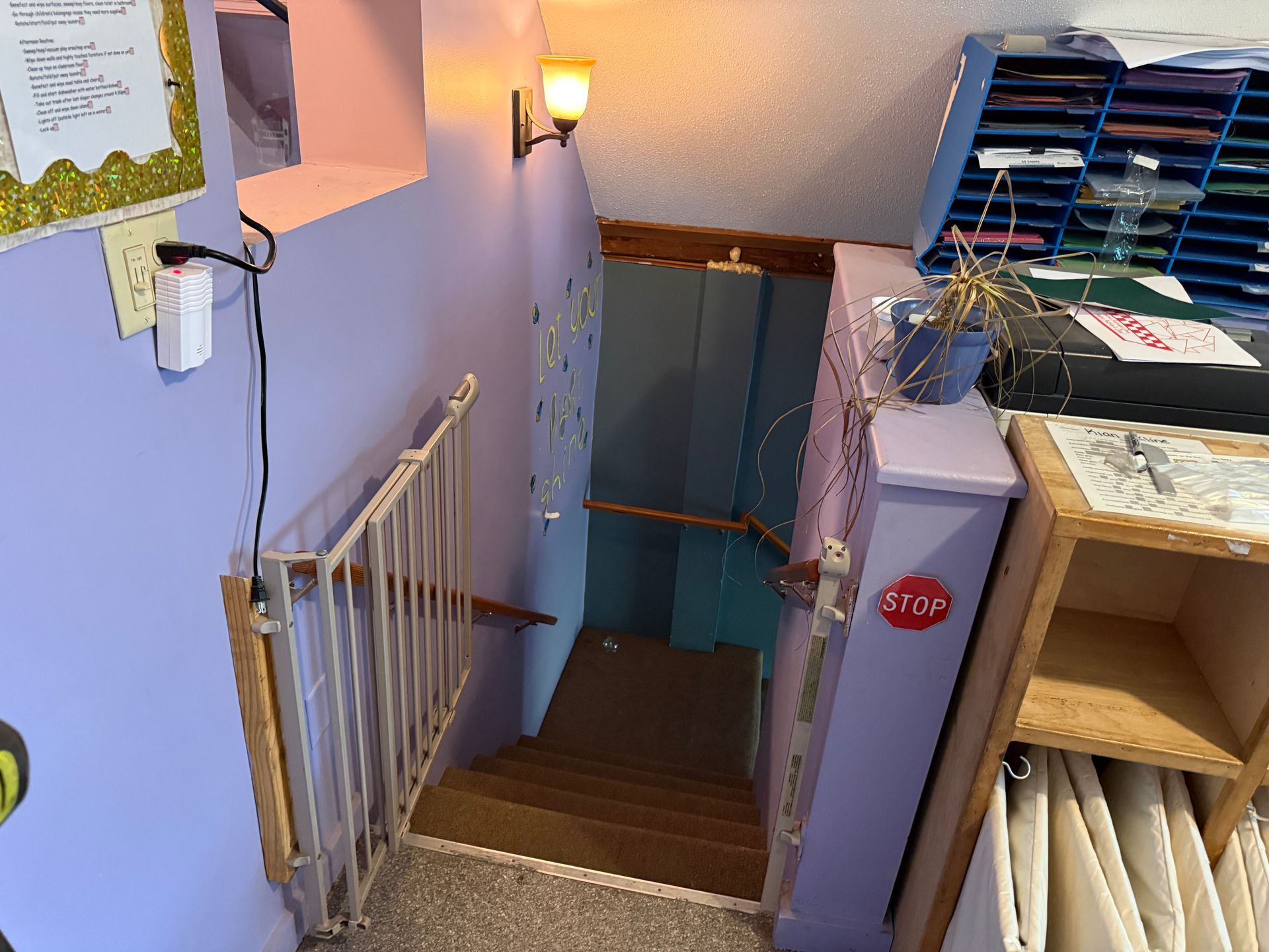 Narrow stairwell with blue walls, wooden steps, and shelves stacked with folders and papers.