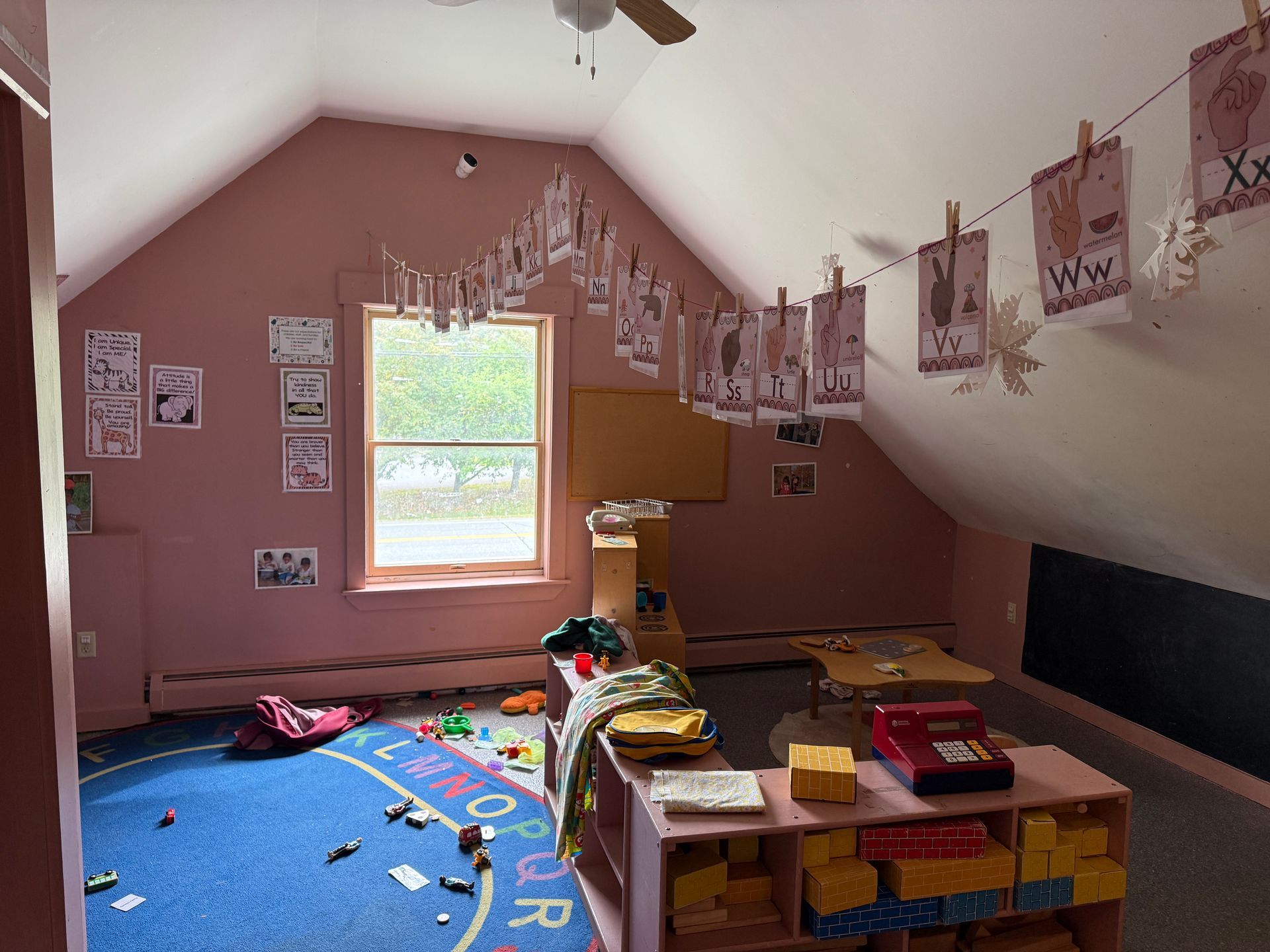 Kids’ playroom with blue rug, hanging art, and a window under a sloped ceiling