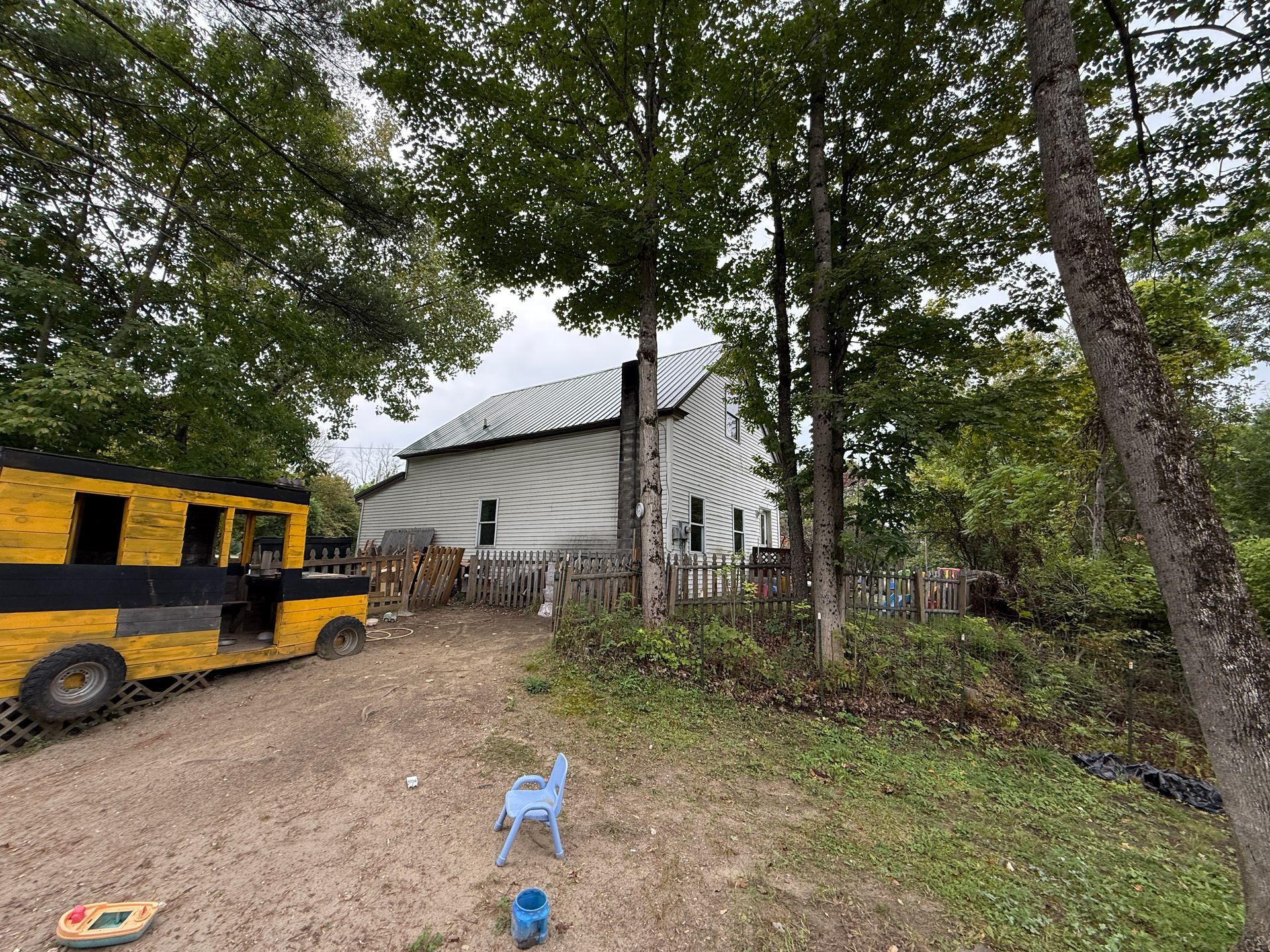 White house in wooded yard with yellow utility vehicle