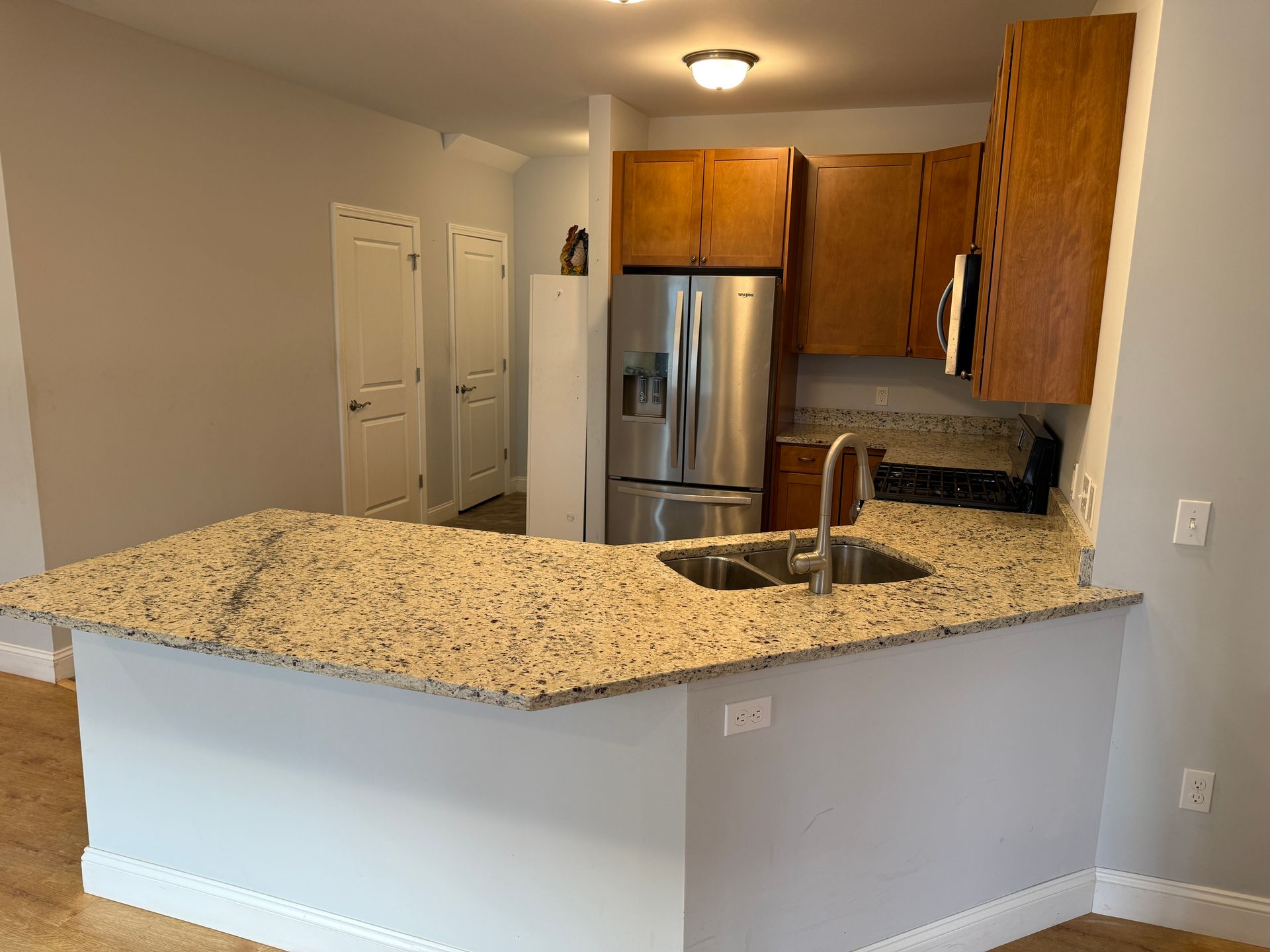 Bright kitchen with granite island, stainless steel refrigerator, and wood cabinets