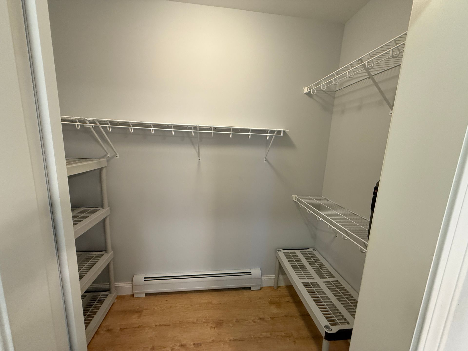Empty walk-in closet with wire shelving and light wood floor.