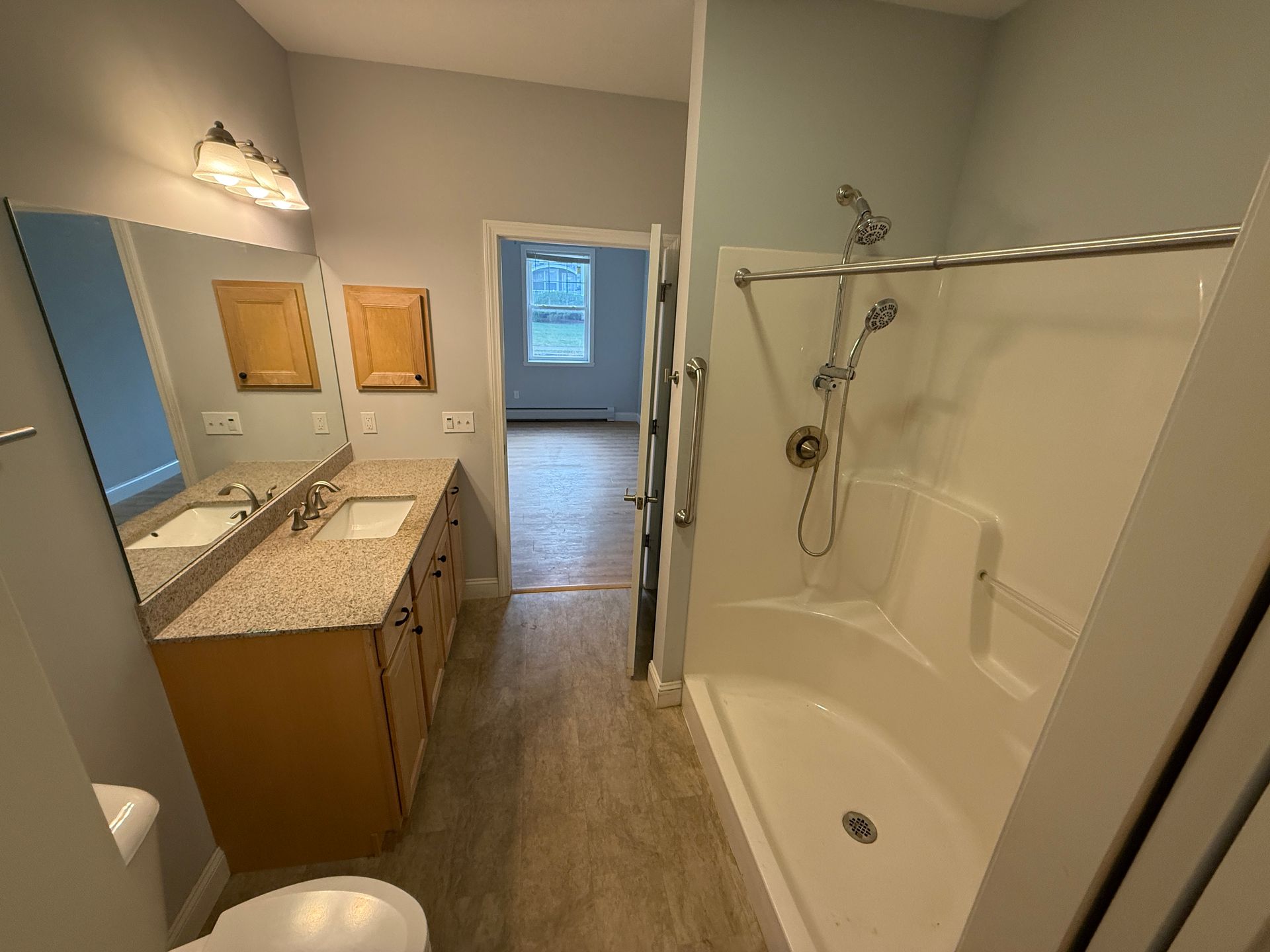 Bathroom with vanity, mirror, walk-in shower, and tub visible through an open door.