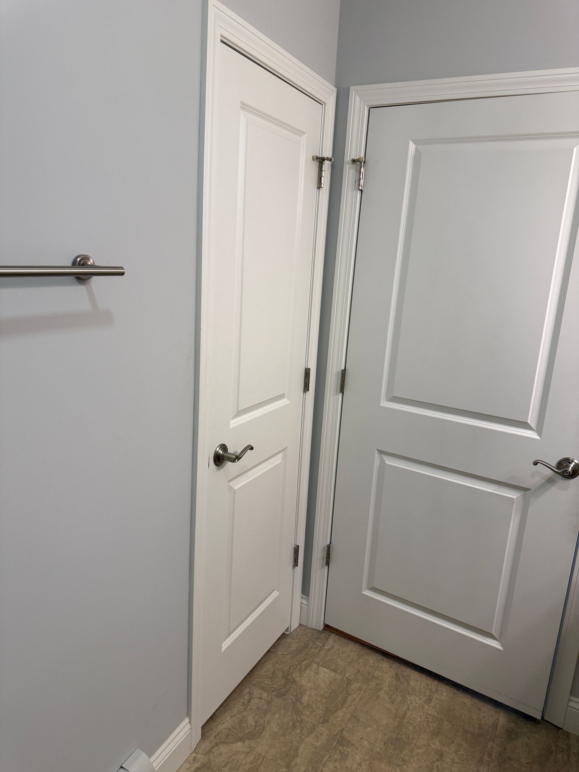 Two white paneled doors in a corner of a carpeted room, one partially open.
