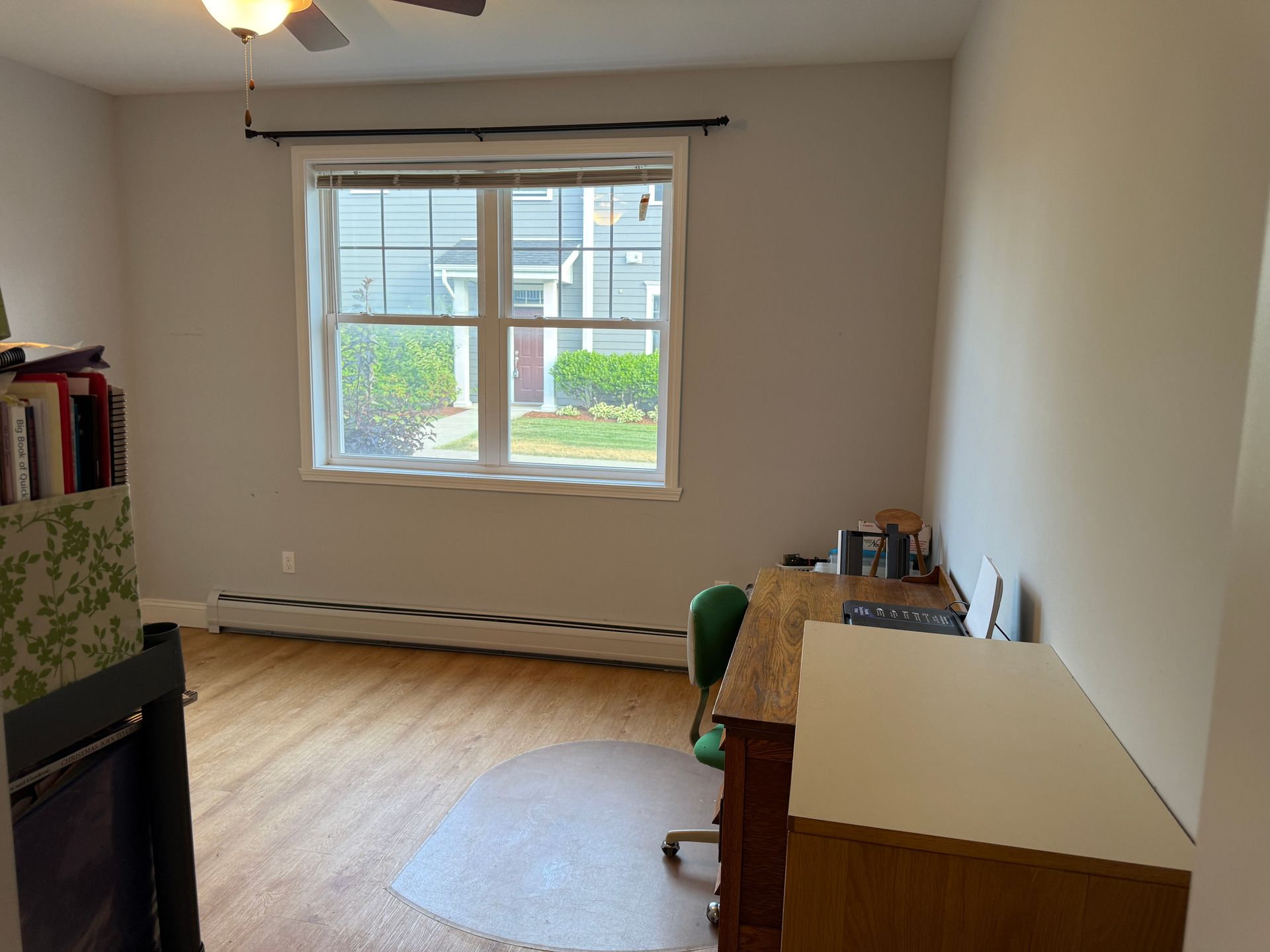 Empty room with wood floor, window, and desk along the right wall.
