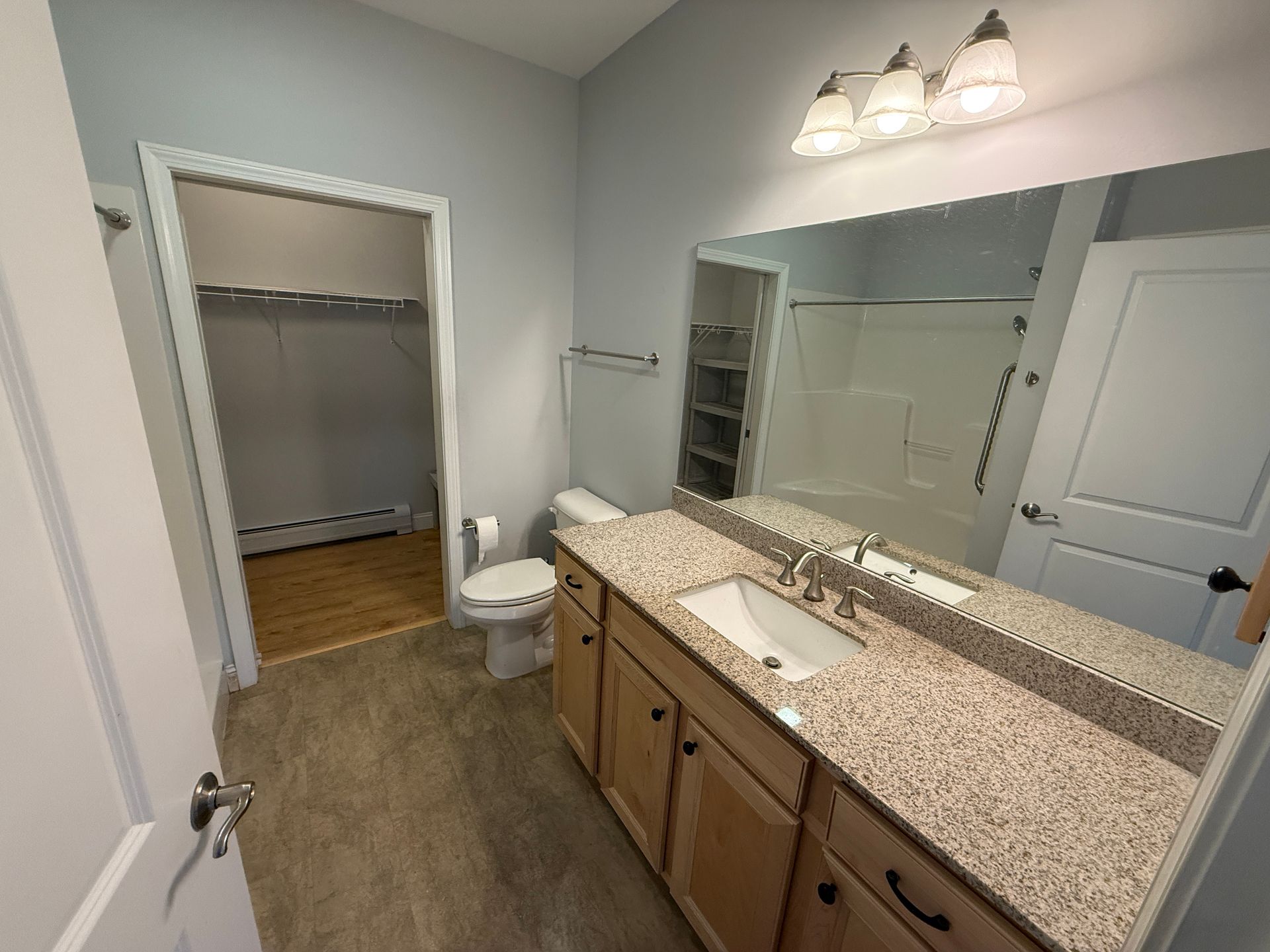 Bathroom with double vanity, large mirror, and open closet visible in the background.
