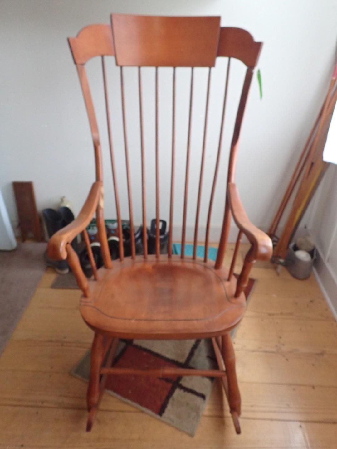 Wooden rocking chair on a tiled floor, viewed from the front.