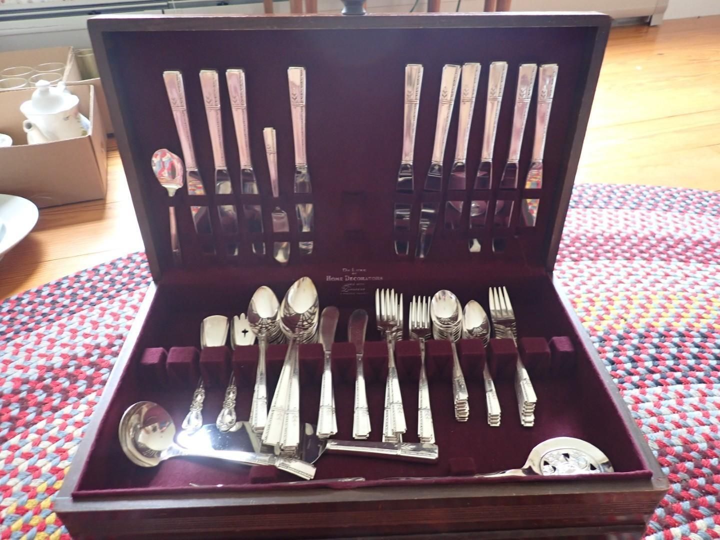 Open wooden cutlery case with silverware neatly arranged on a patterned rug