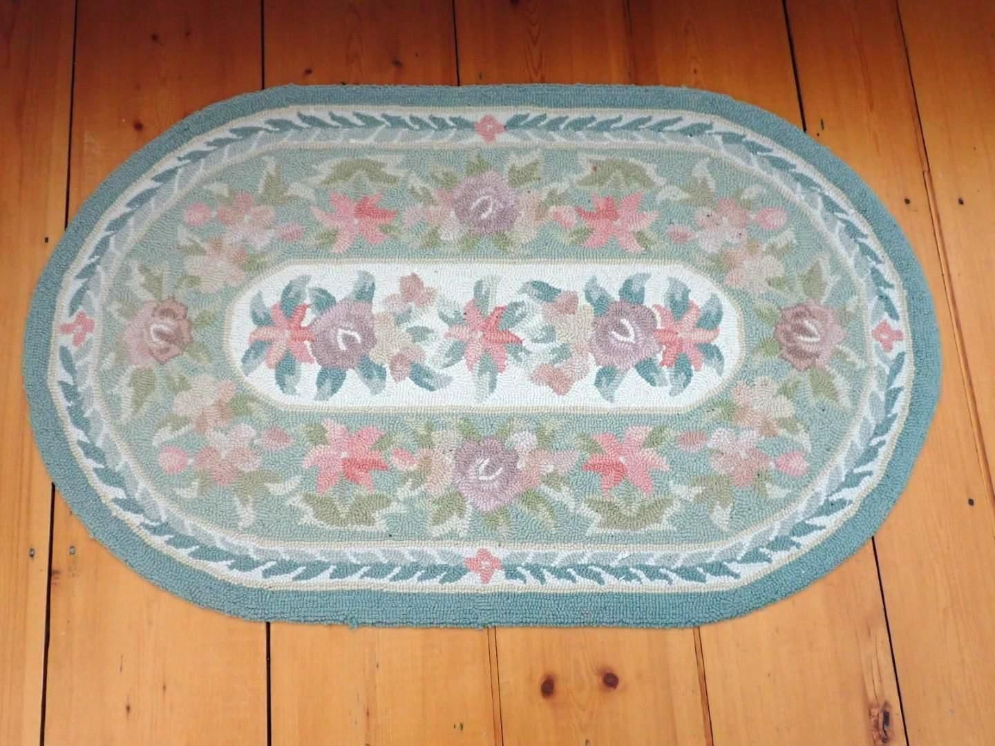 Oval floral rug in blue, pink, and green on a wooden floor