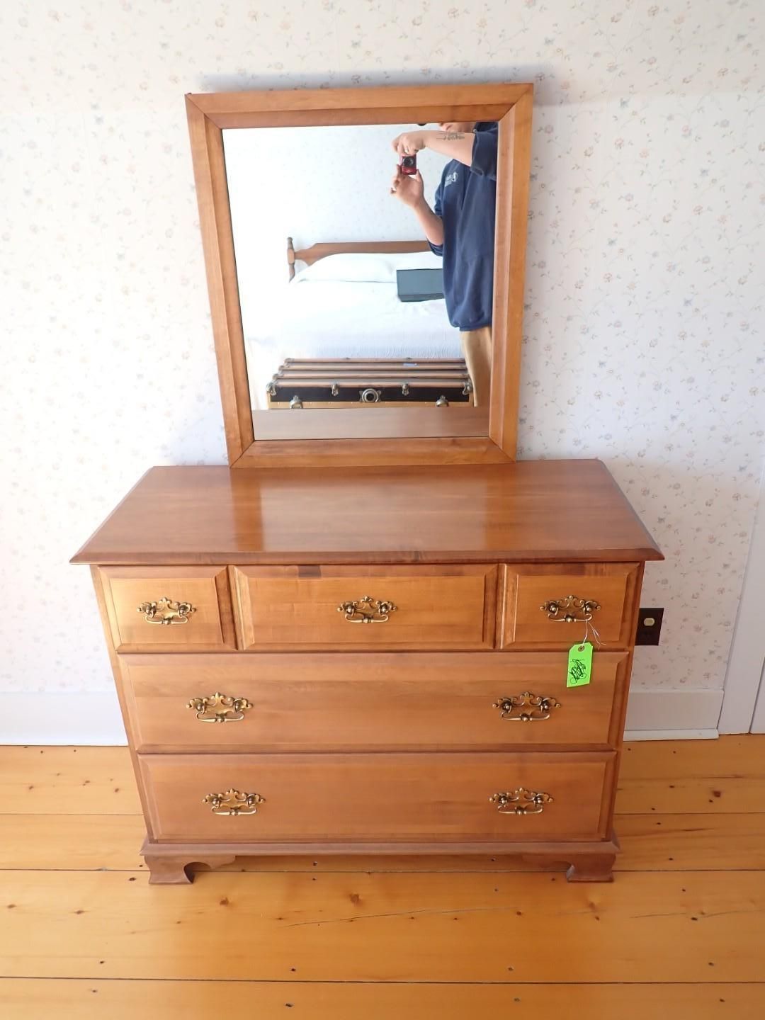 Wooden dresser with mirror in a lightly patterned room