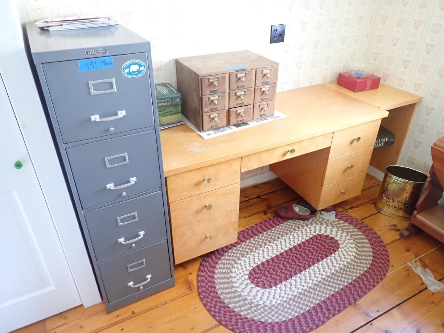 Office desk with drawers, gray filing cabinet, and a small rug on a wooden floor.