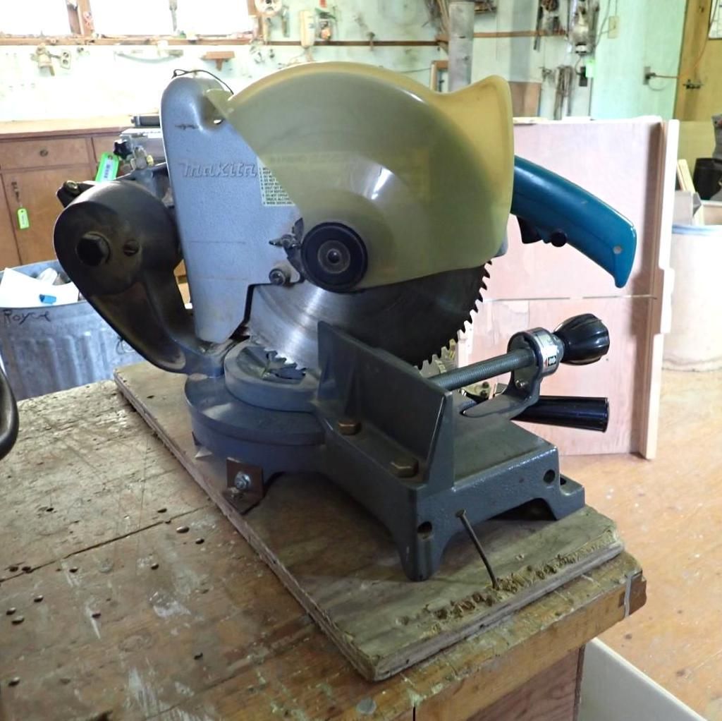 Grey-and-blue circular miter saw on a wooden workbench in a workshop