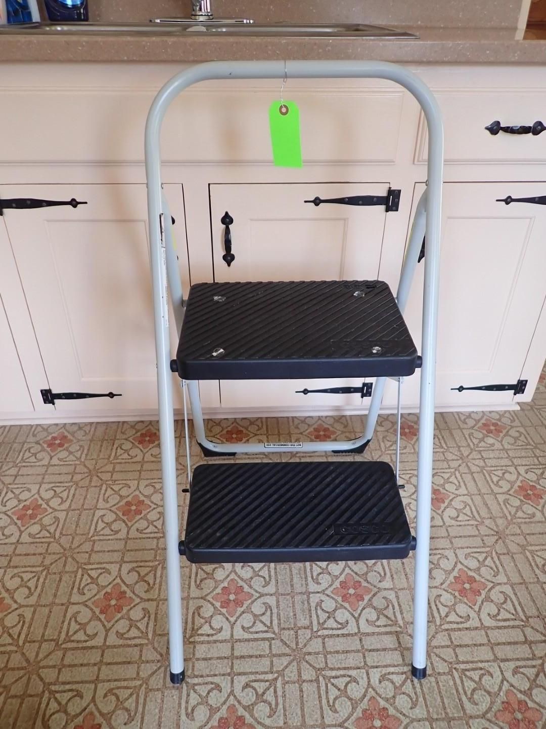 Small folding step stool with black textured steps and silver frame in a kitchen.