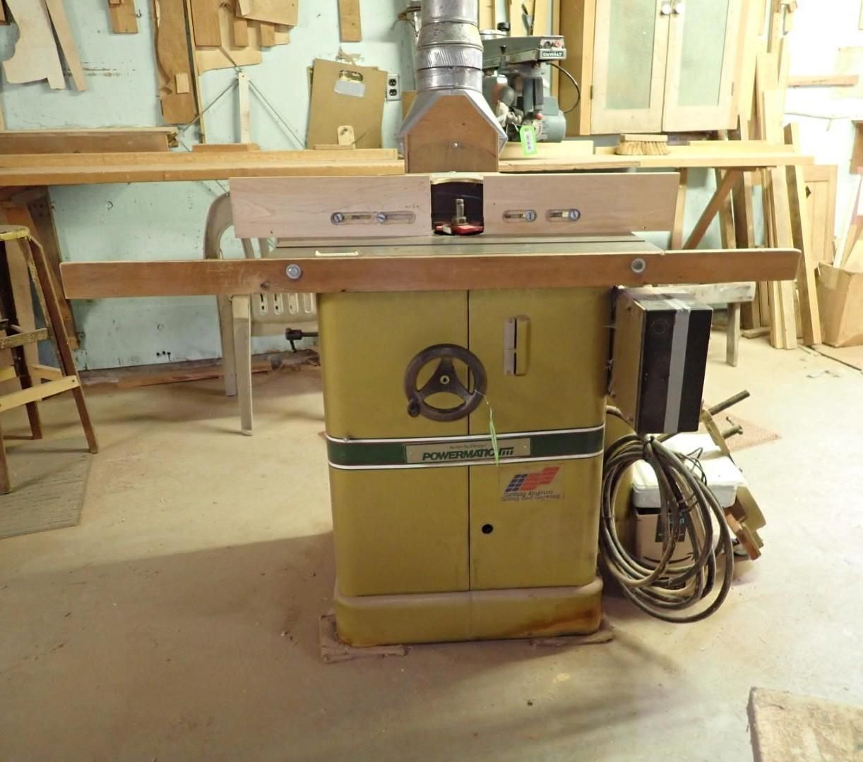 Yellow table saw in a workshop, with wood pieces and coiled power cord nearby