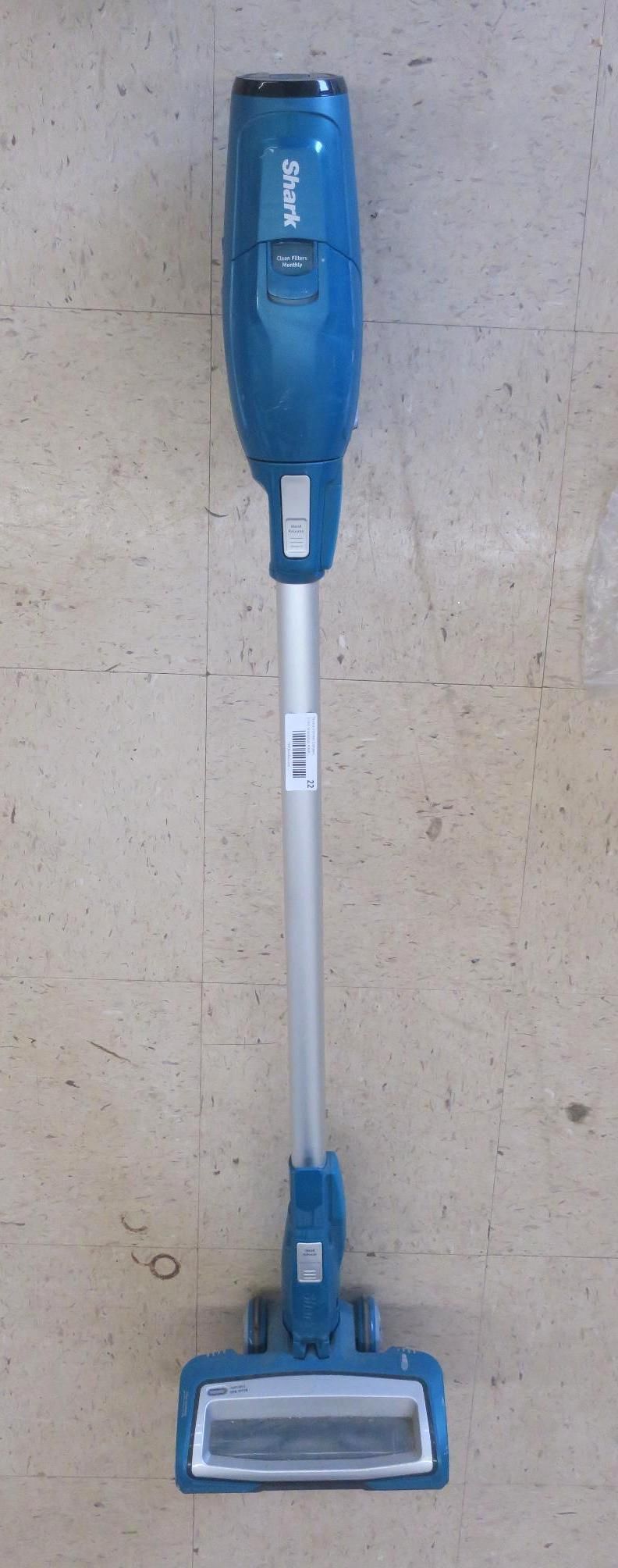 Blue cordless stick vacuum cleaner standing upright on a plain surface.
