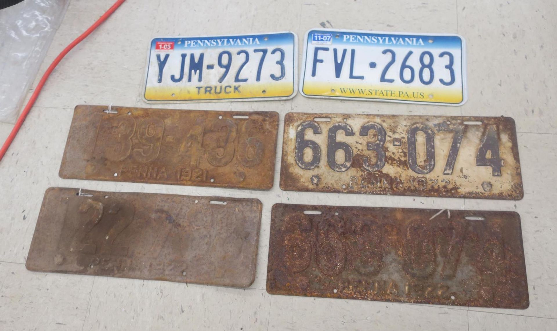 Six license plates laid out on a surface, including blue-yellow truck plates