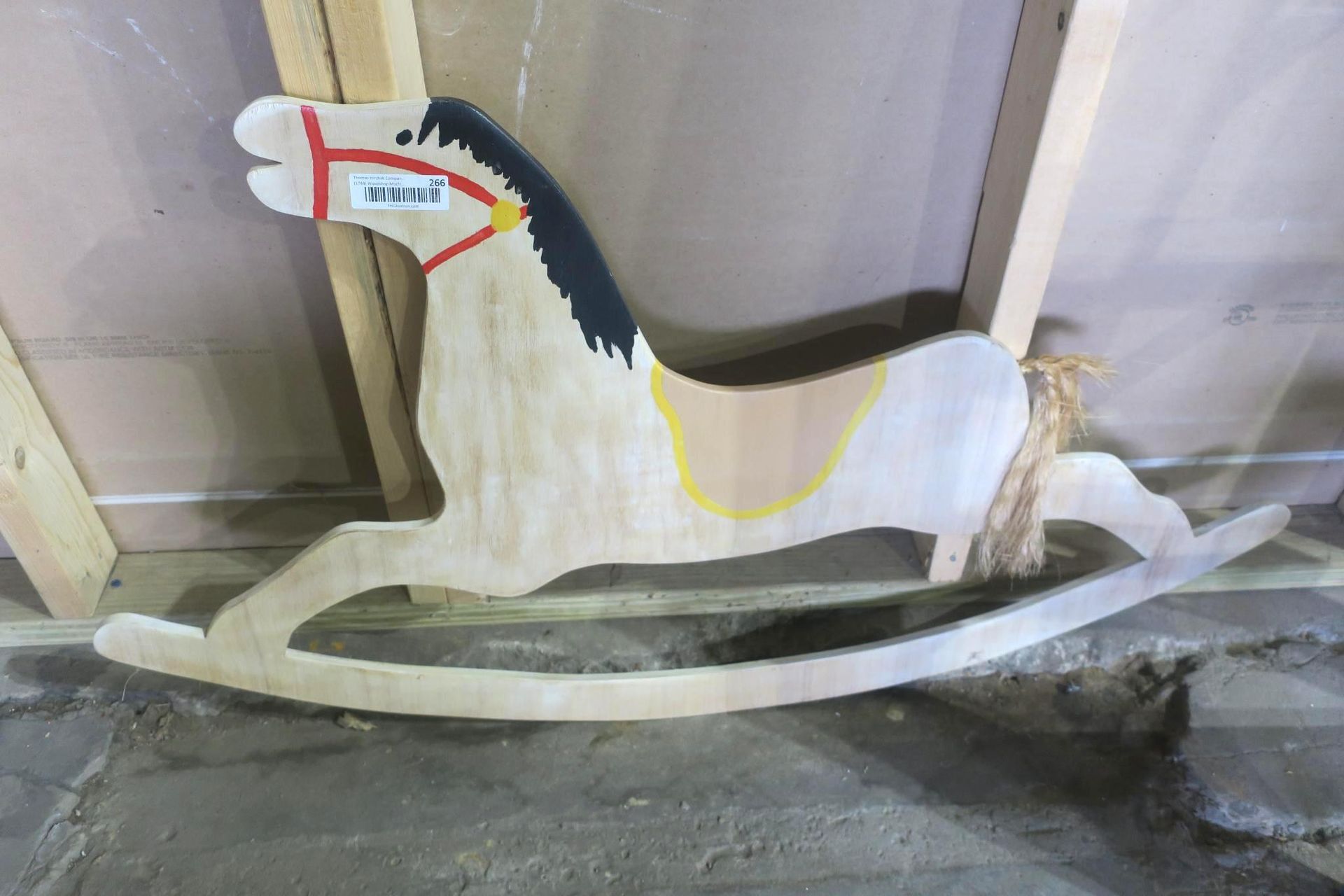 Wooden rocking horse with painted mane and saddle, displayed indoors on a floor