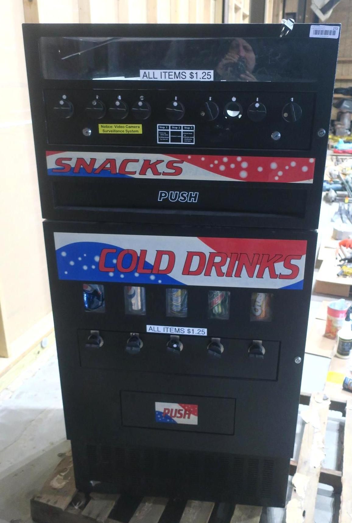 Black vending machine with snack and cold drink sections in a store.
