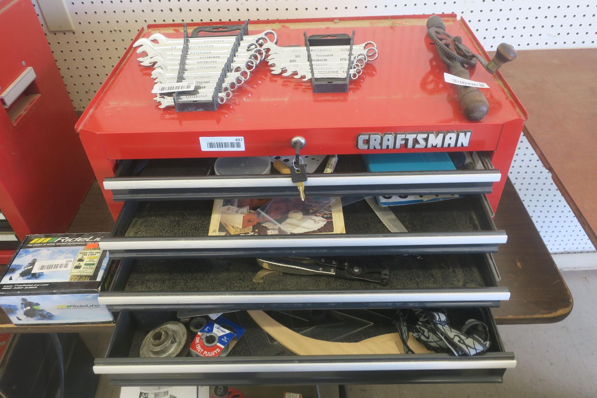 Red Craftsman tool chest with open drawers and assorted tools in a workshop aisle