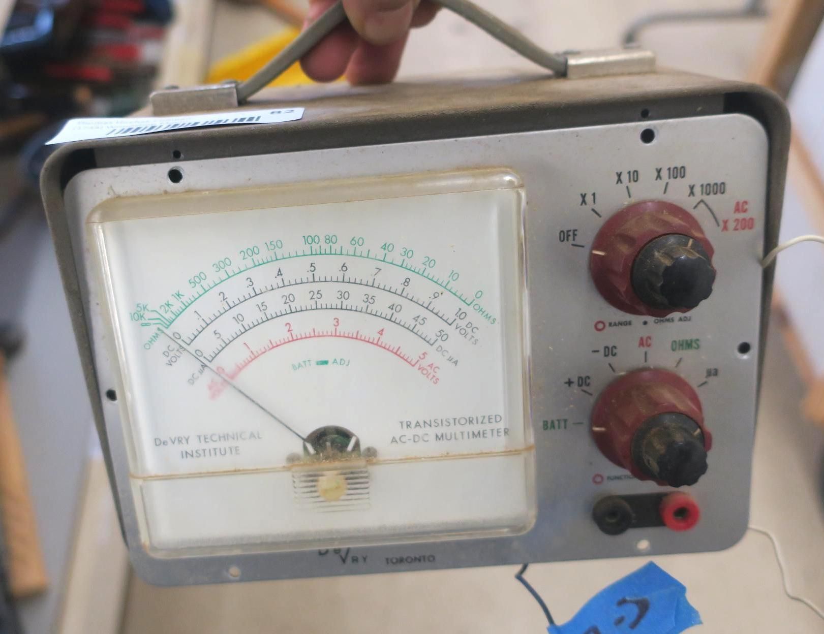 Vintage analog electrical meter with two red adjustment knobs and a display scale.