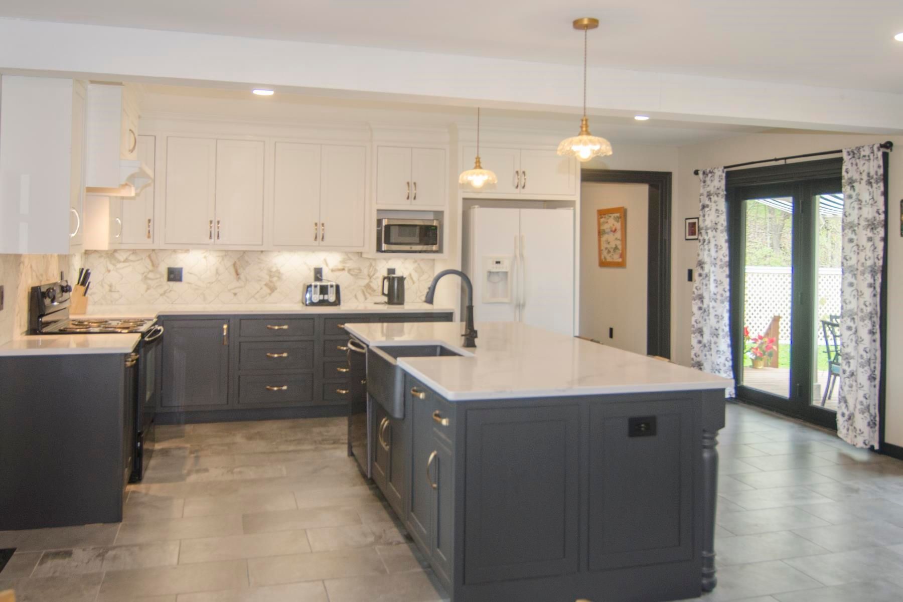 Modern kitchen with gray and white cabinets, large island, and French doors.