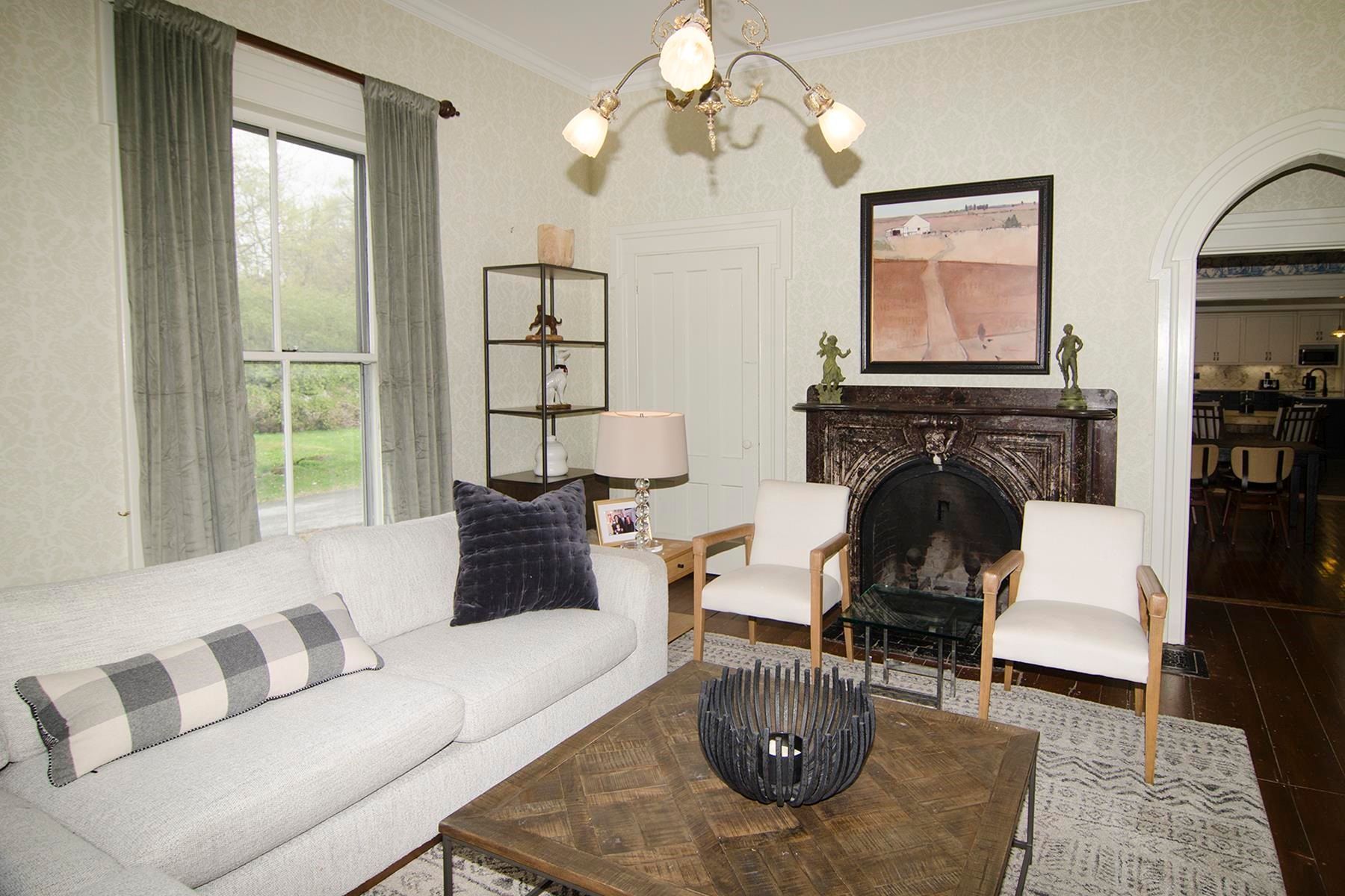 Living room with white sofa, chairs, fireplace, artwork, and chandelier.