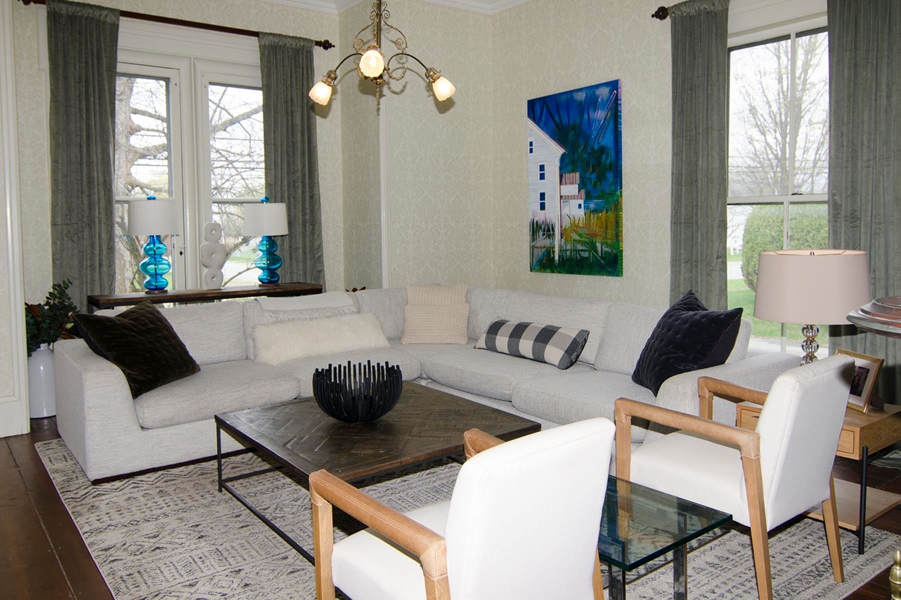 Living room with white sectional sofa, two chairs, and a painting; blue, gray, and wood tones.