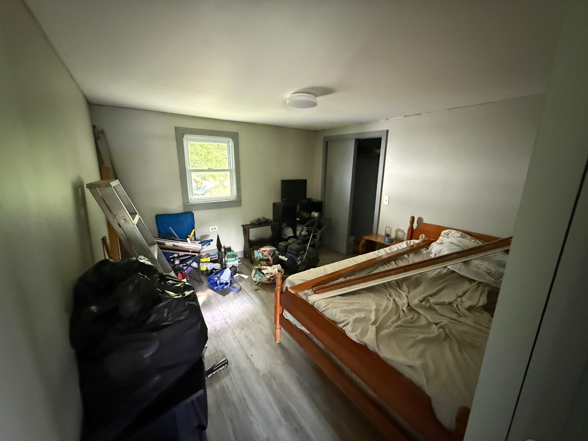 bedroom with a wooden bed and a small window letting in daylight