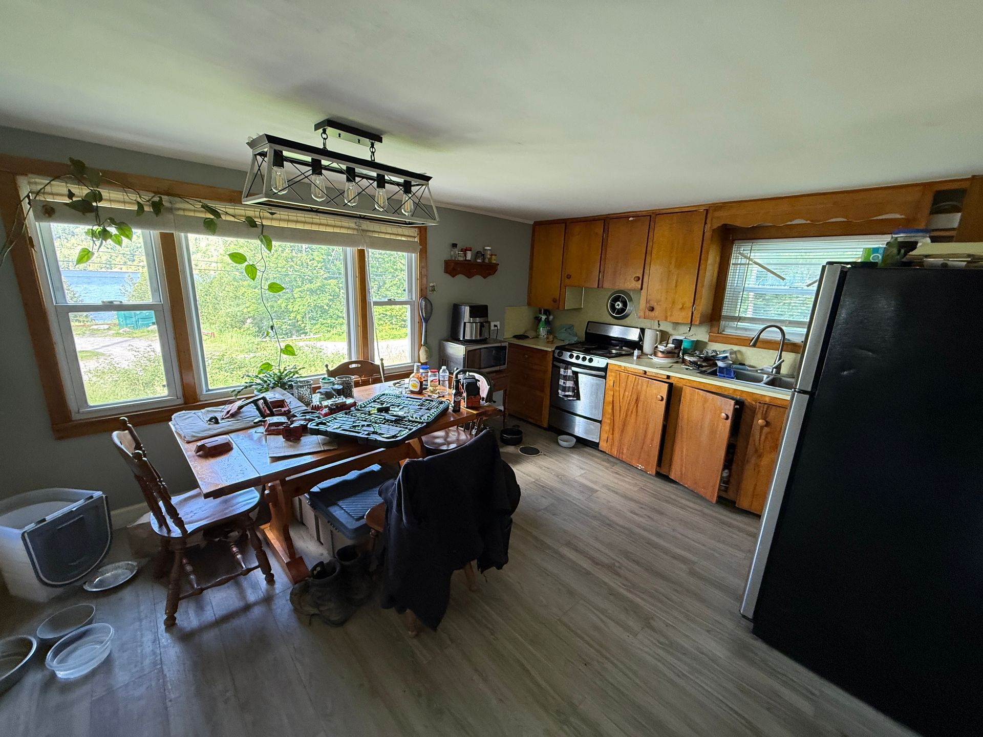 kitchen-dining room with wooden cabinets, large windows, and a black refrigerator