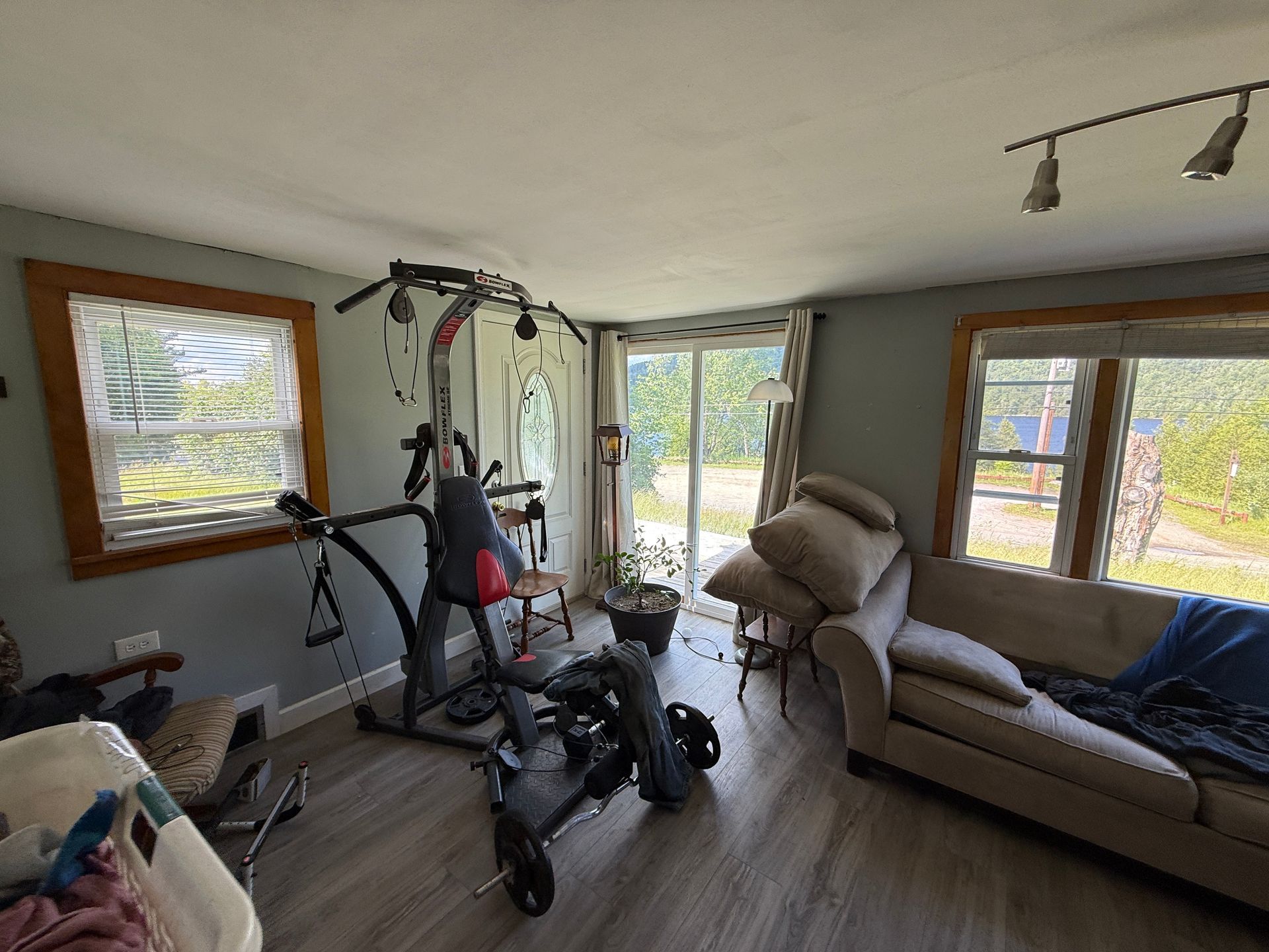 living room with exercise equipment, beige couch, and large windows overlooking a yard