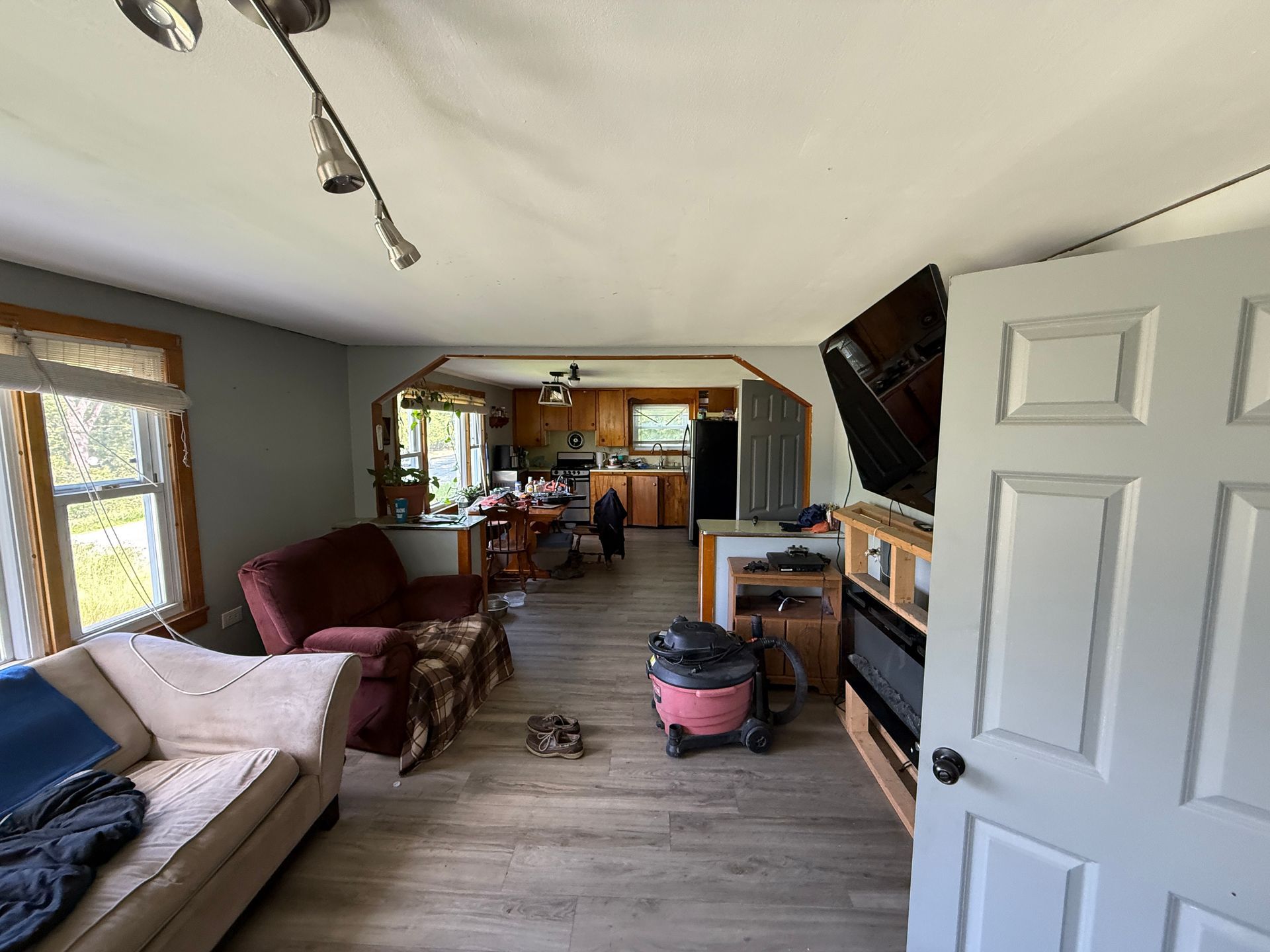 living room with couch, chairs, TV, and open doorway leading to a kitchen