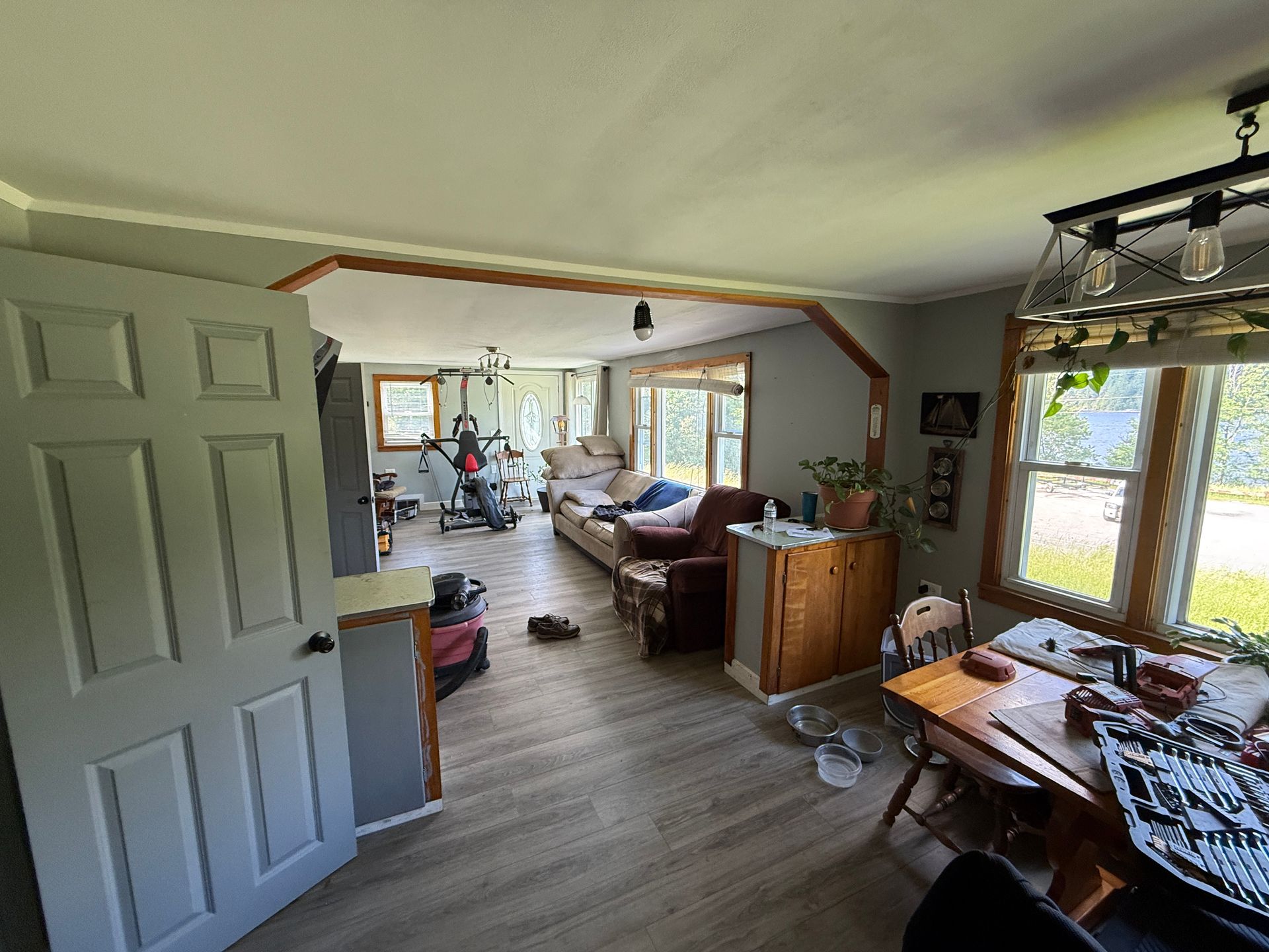Living room with large windows, wooden floors, sofa, and dining table in a bright home interior