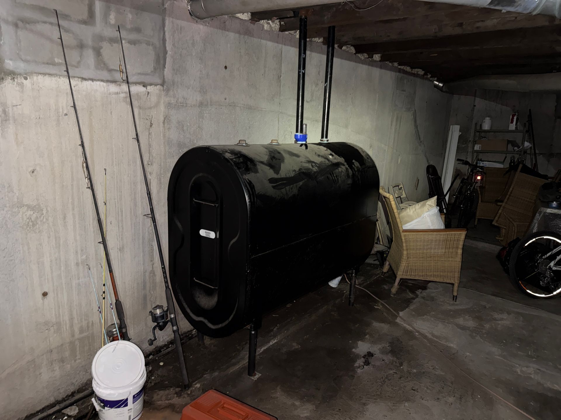 Black cylindrical tank in a basement beside a wall