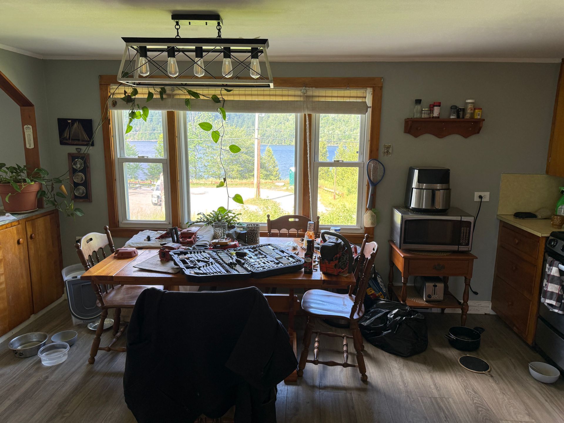 Bright dining room with a table, chairs, large window, and shelves, lit by daylight.