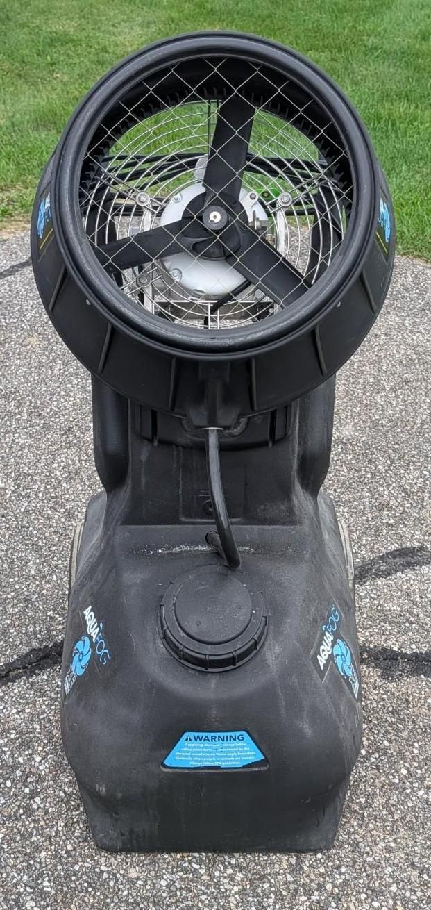 Black portable fan on a wheeled base outdoors, facing forward.
