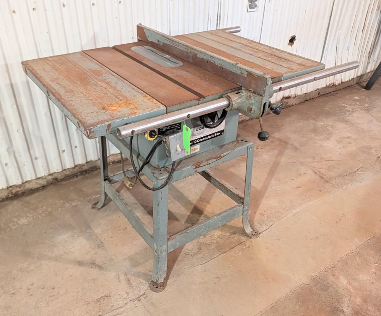 industrial table saw with a metal top and green base in a workshop area