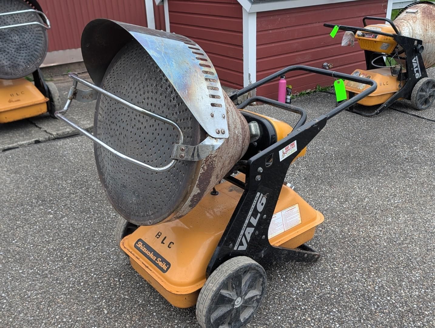 Outdoor view of a black-and-orange electric heating cart loaded with metal parts.
