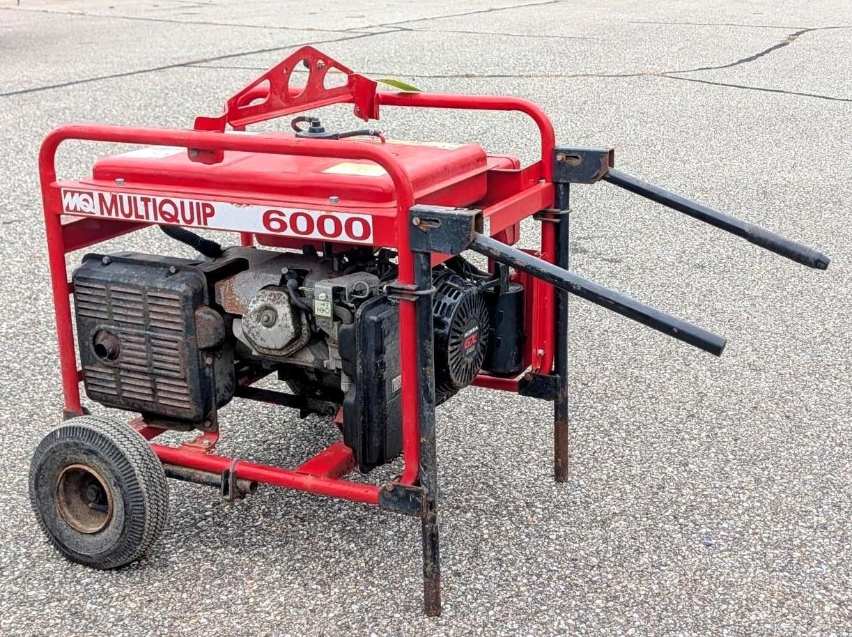 Red portable generator on a wheeled frame with two handles, sitting on pavement.