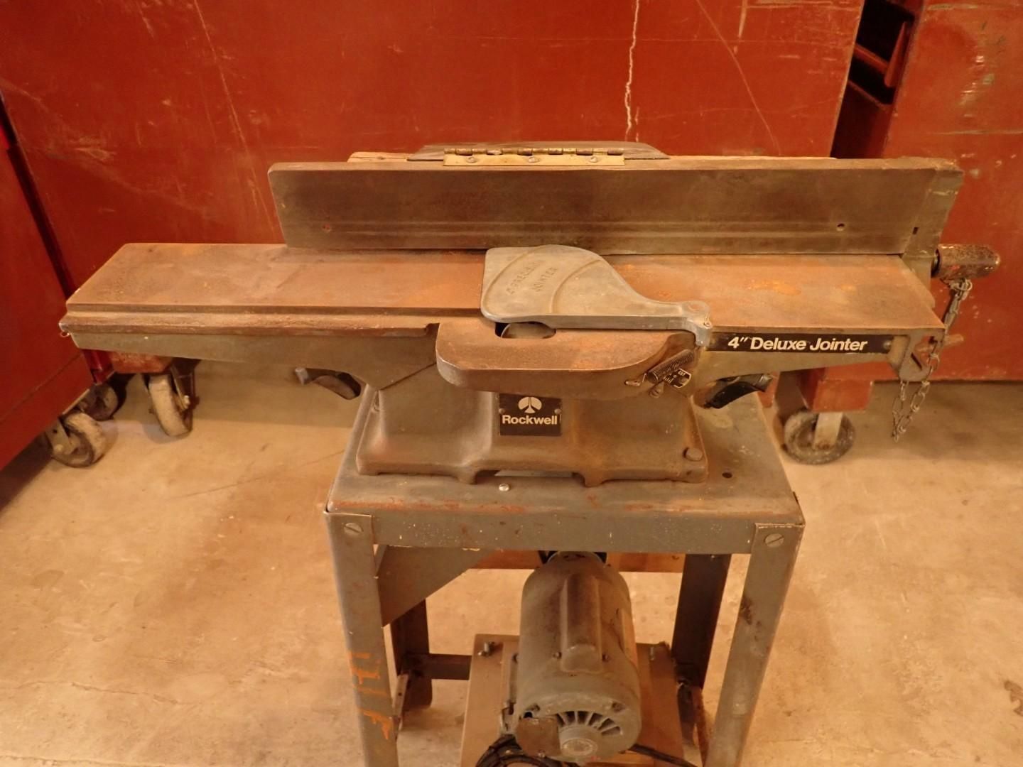 table saw in a workshop, with red walls and a gray metal stand.