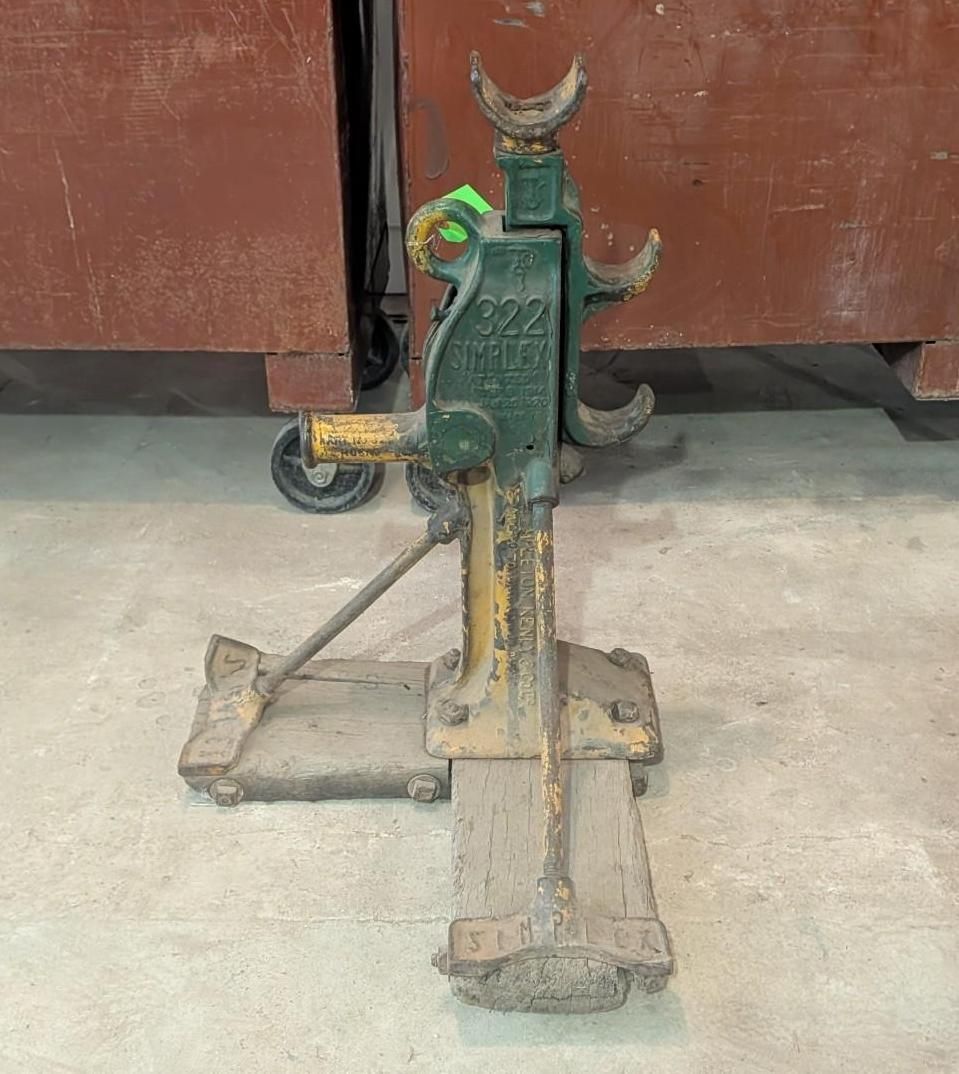 green metal jack standing on a concrete floor in front of a brown cabinet.