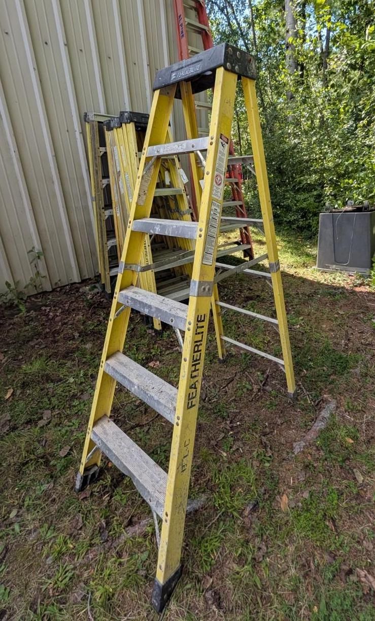 Yellow step ladder leaning beside a building on grass outdoors