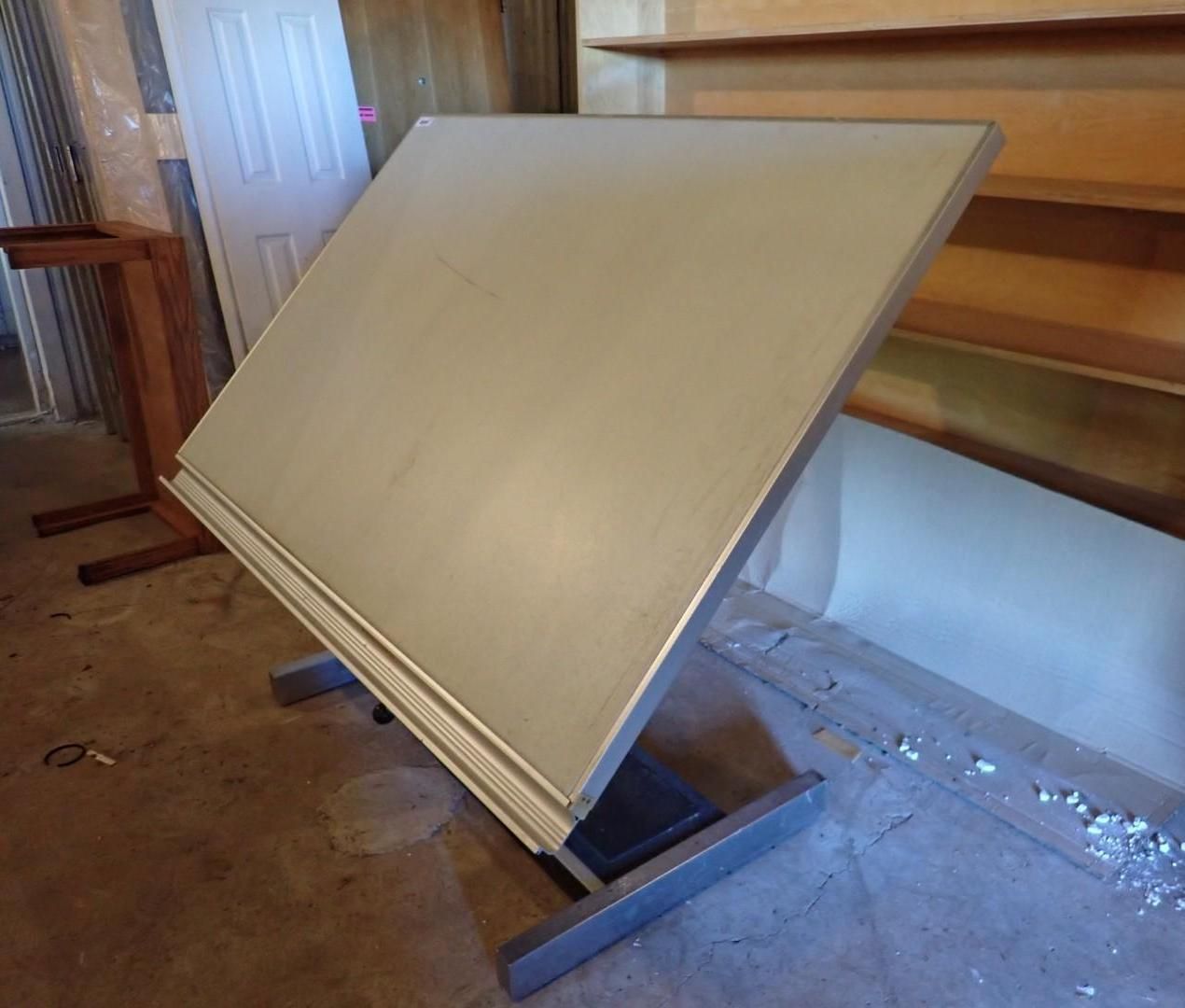 Large blank display board on a floor stand in a room with wood-paneled walls and a window.