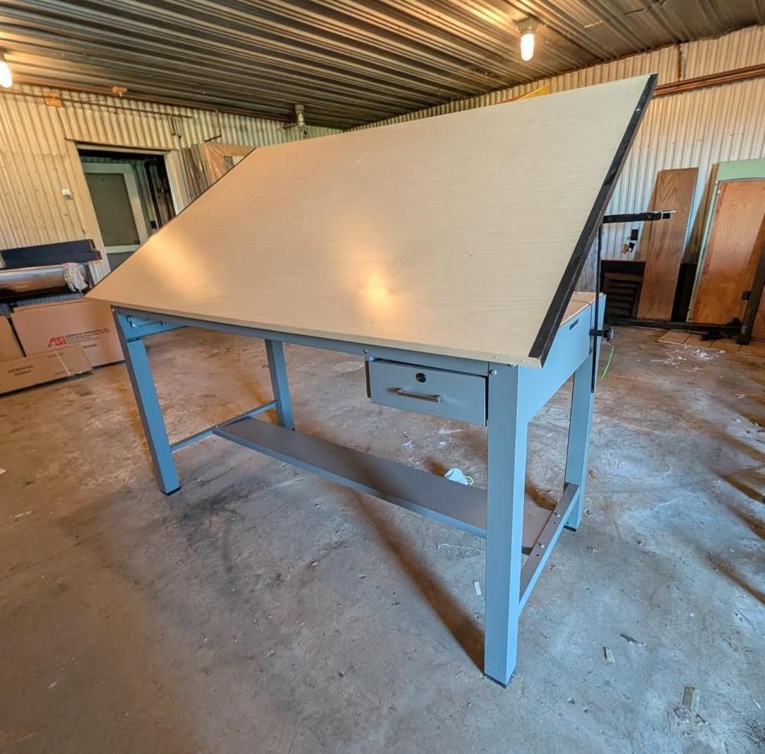 Large tilted gray worktable in a warehouse with a metal roof and concrete floor
