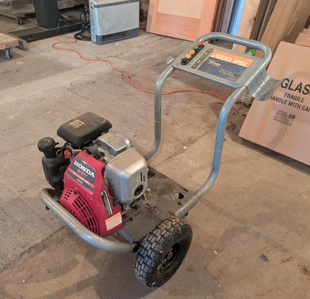 Small red-and-gray wheeled generator on a concrete floor in a workshop area