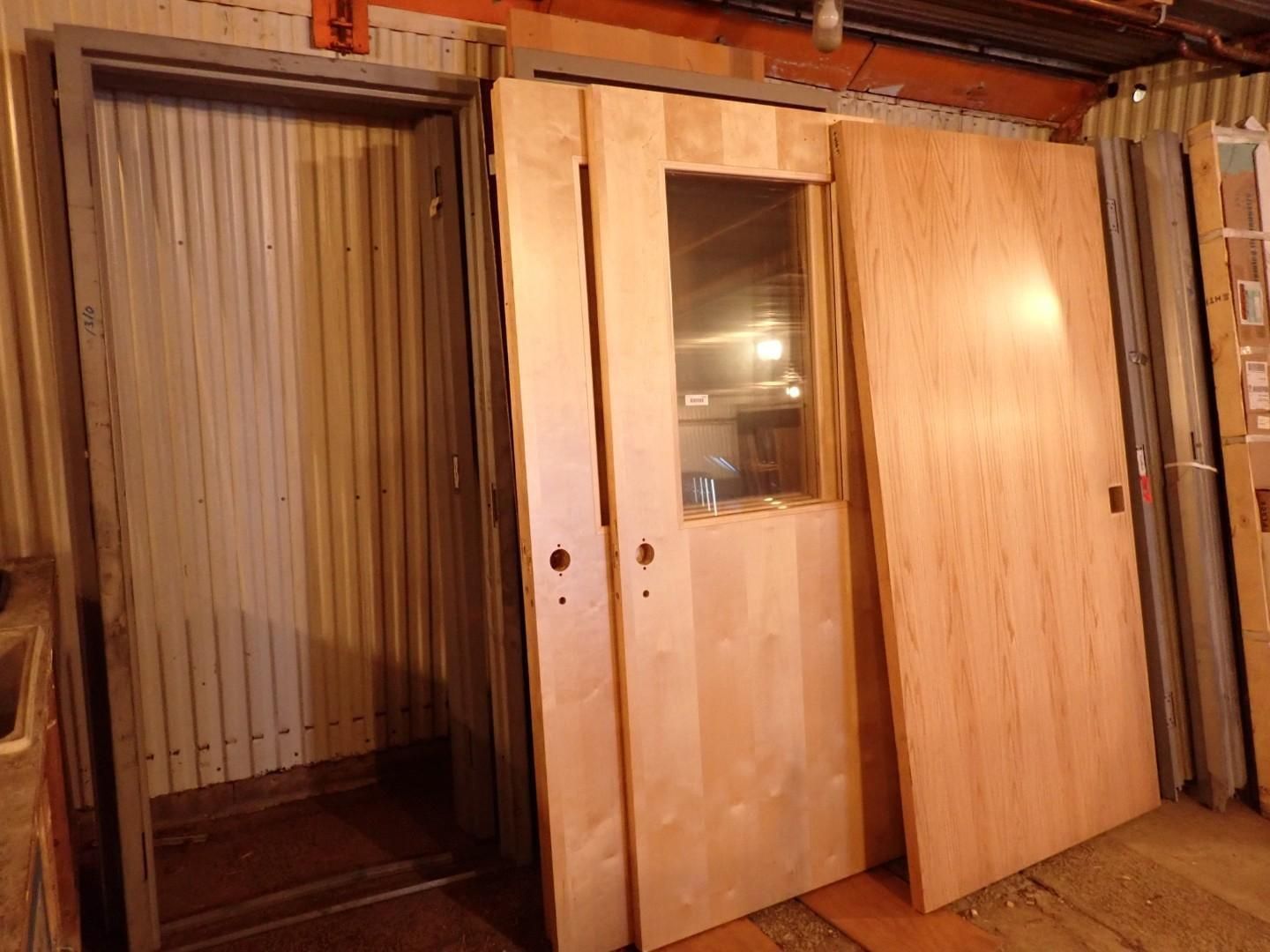 Two wooden doors leaning in a storage area, one with a small window.