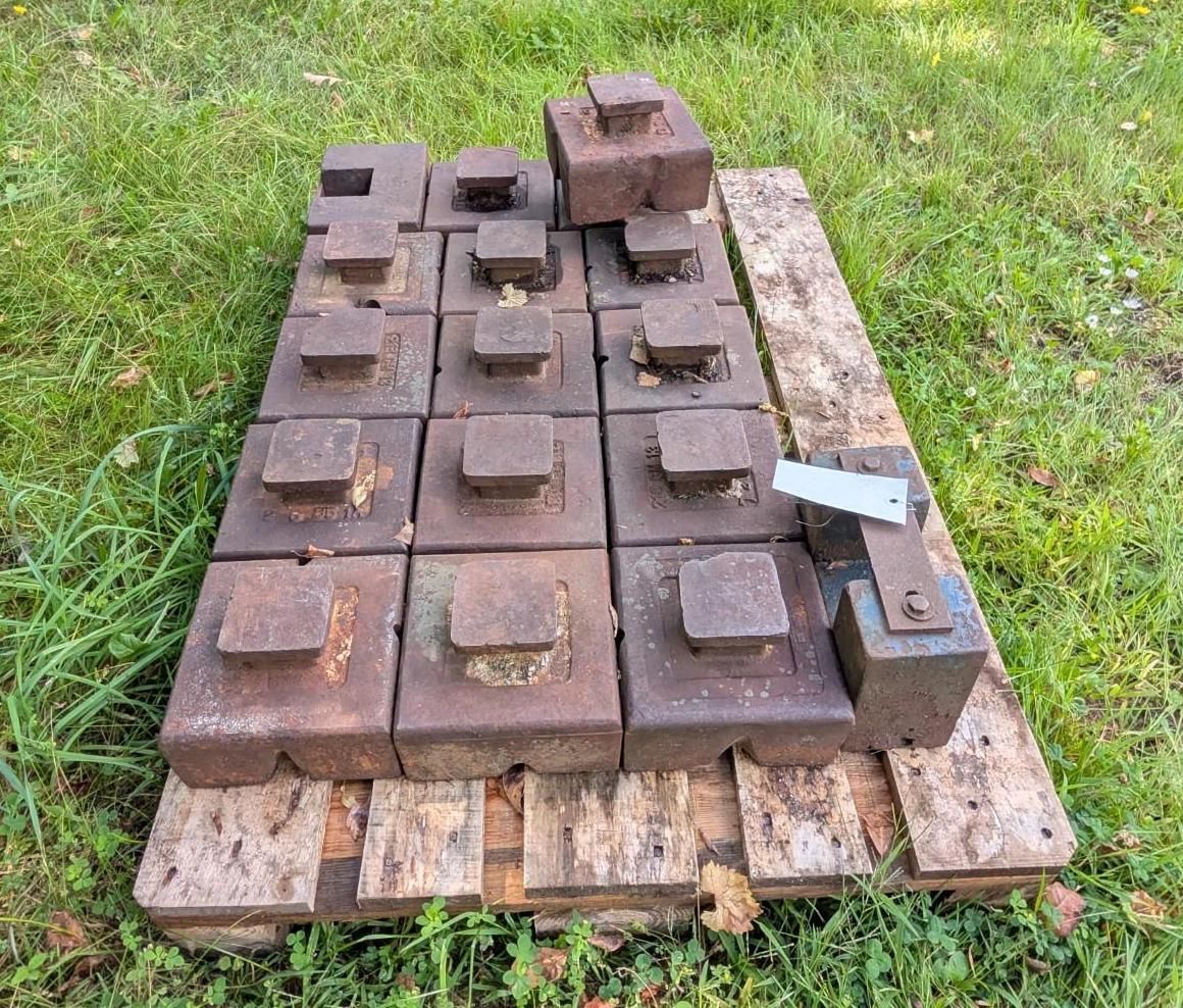 metal weights stacked on a wooden pallet outdoors on grass