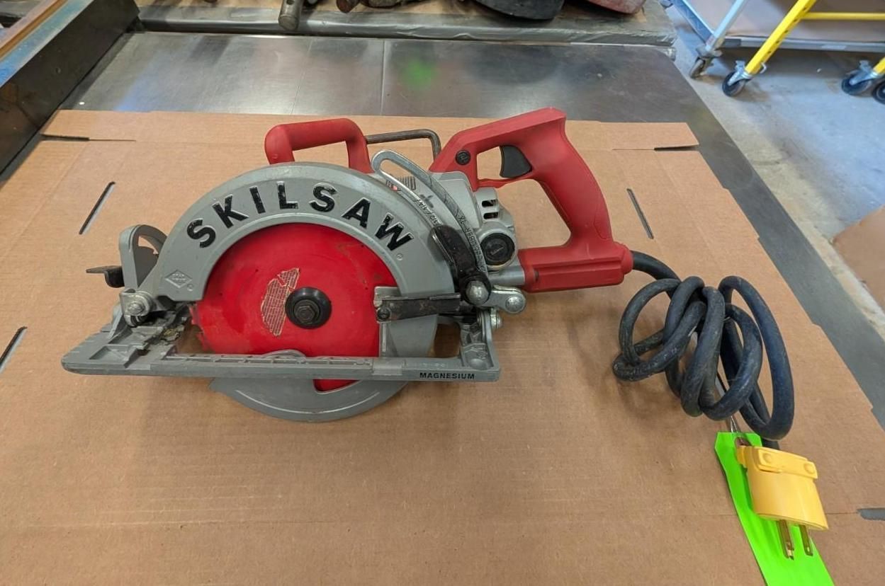 Red SKILSAW circular saw with black cord and yellow plug on a cardboard surface.