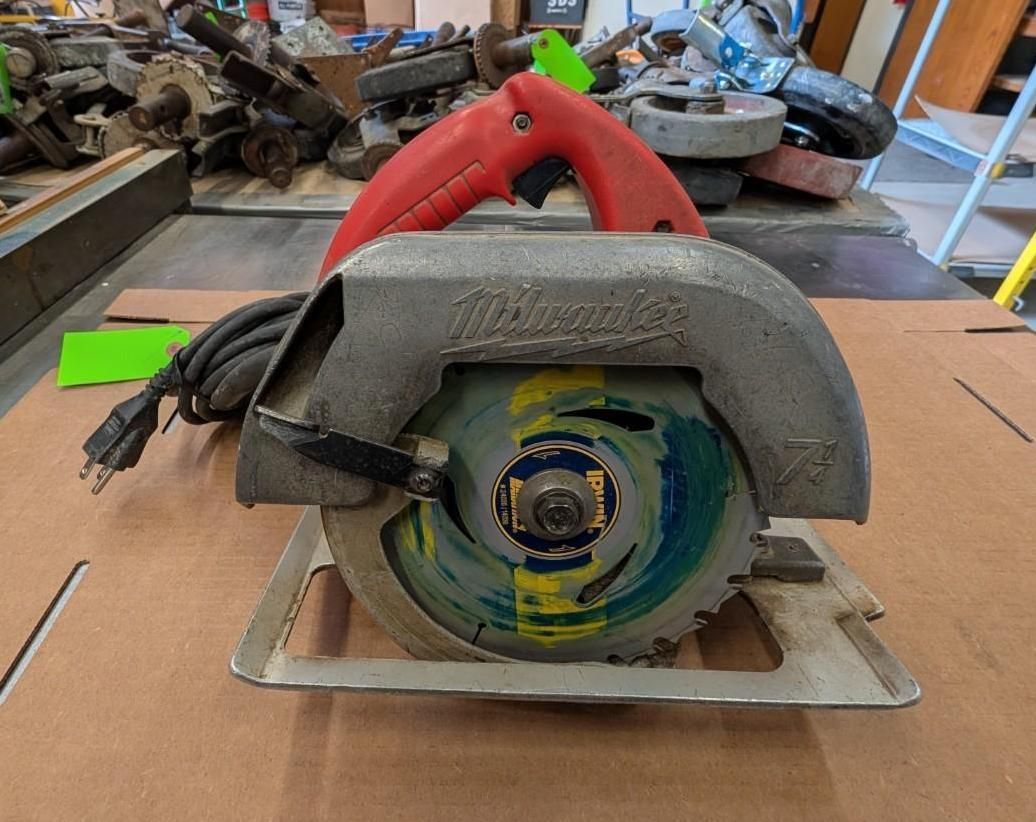 Handheld circular saw on a workbench with a blade guard and red handle, in a workshop setting